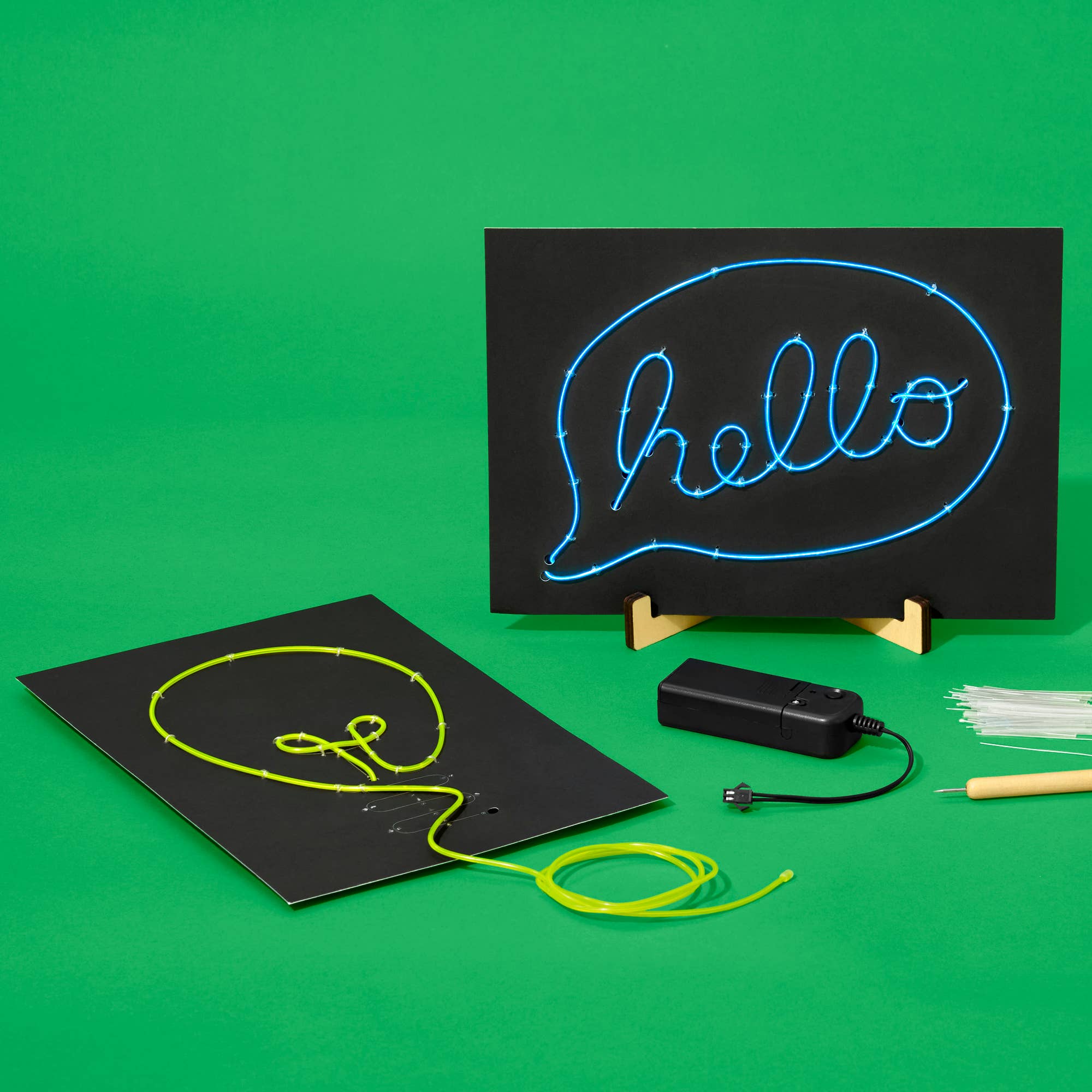 Neon sign with 'hello' text on a black board with components on a green background