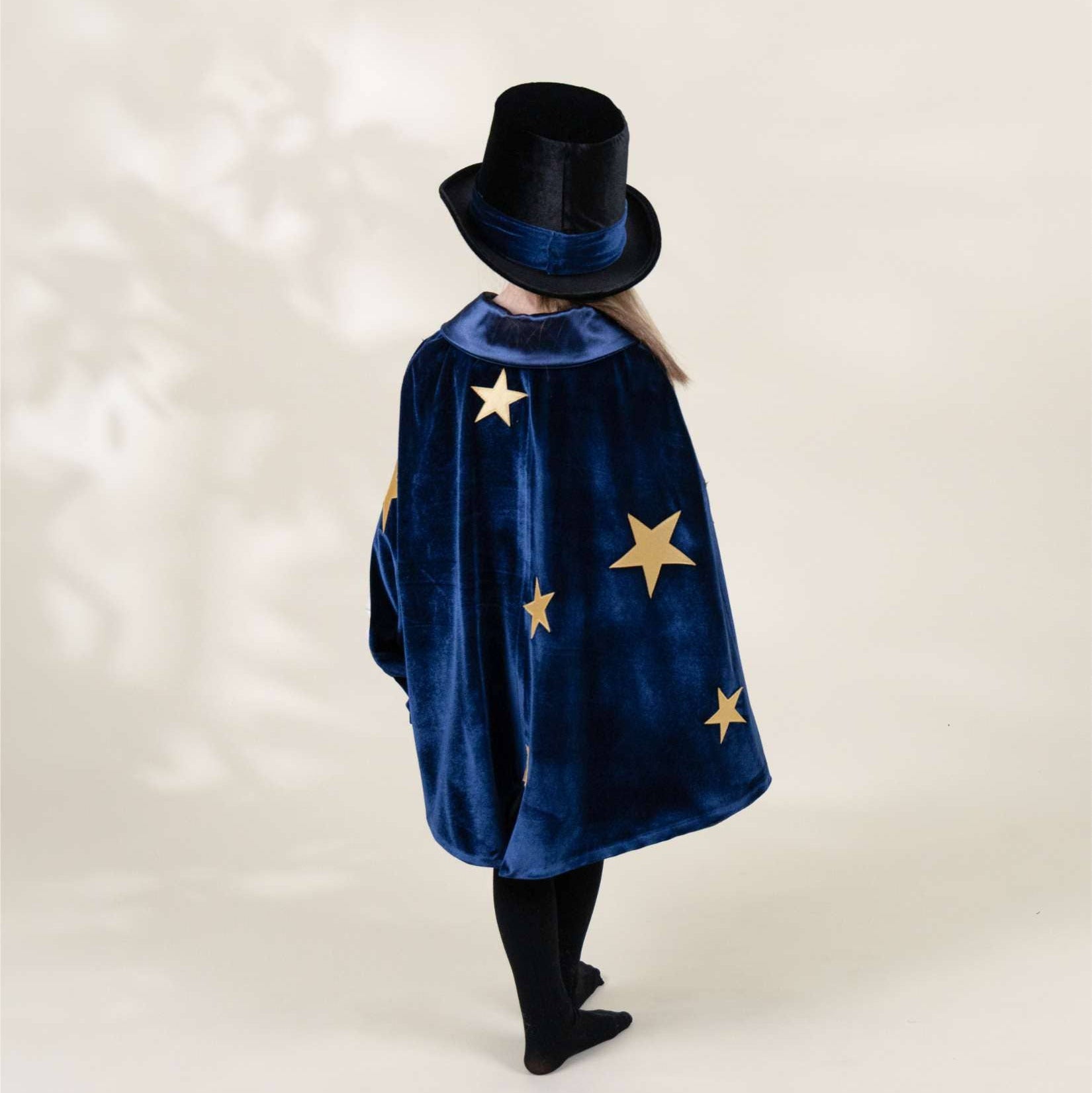 Person wearing a blue cape with star patterns and a black hat on a white background