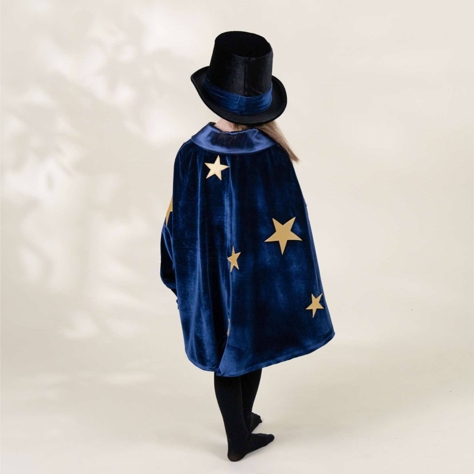 Person wearing a blue cape with star patterns and a black hat on a white background