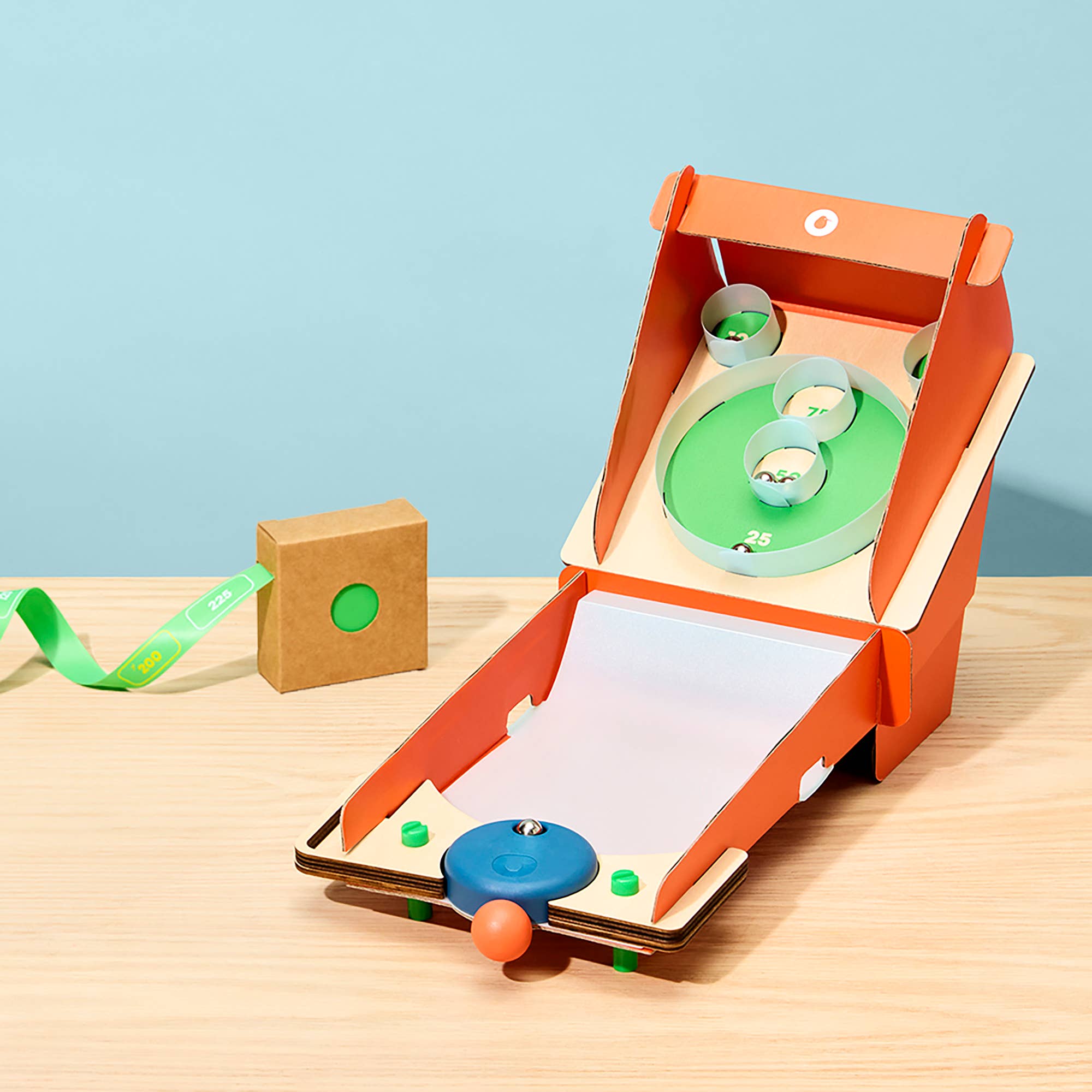 Small wooden arcade game with a blue ball and green cups on a light blue background