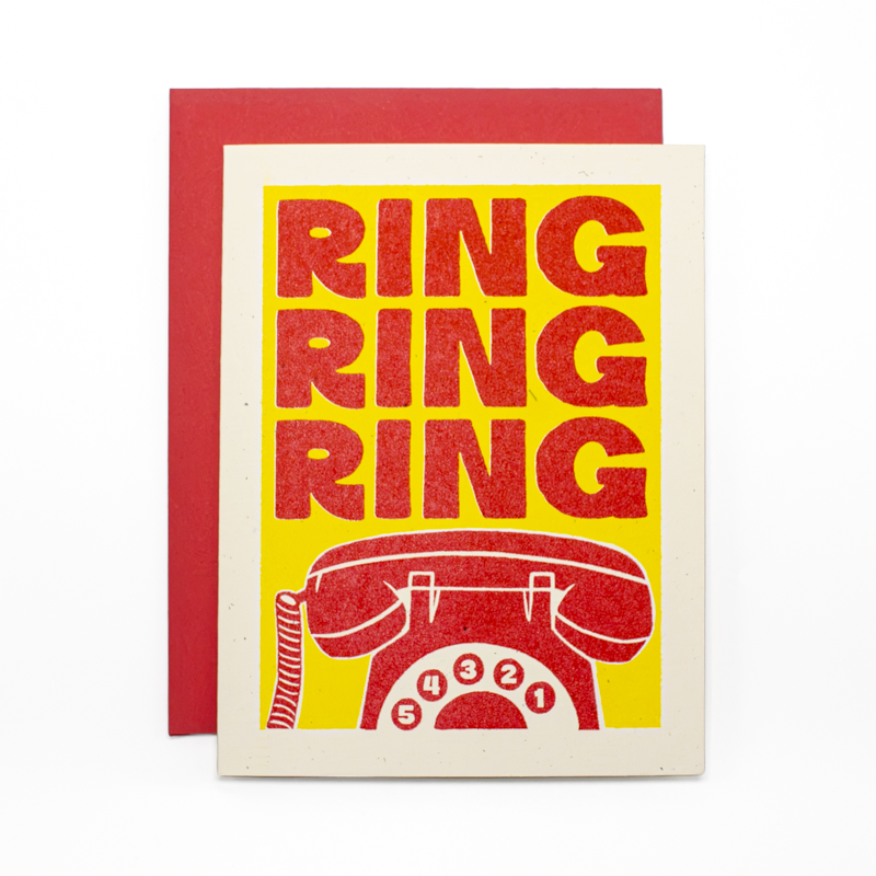 A greeting card with a red envelope, featuring a retro design with the word 'RING' repeated four times in red glitter-style lettering on a yellow background, above a red rotary telephone illustration. The card has a cream border and is photographed on a white background.