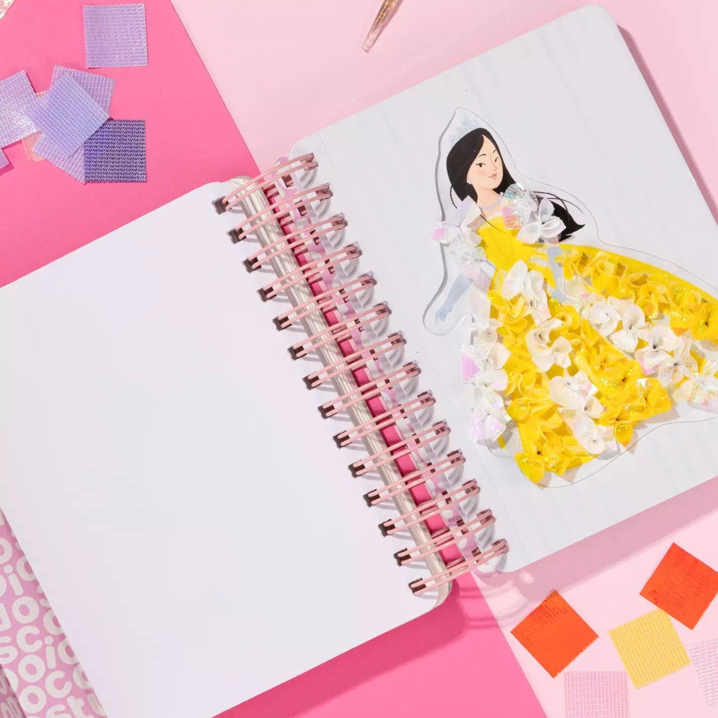 Notebook with a drawing of a princess in a yellow dress on a pink background with colorful square stickers.