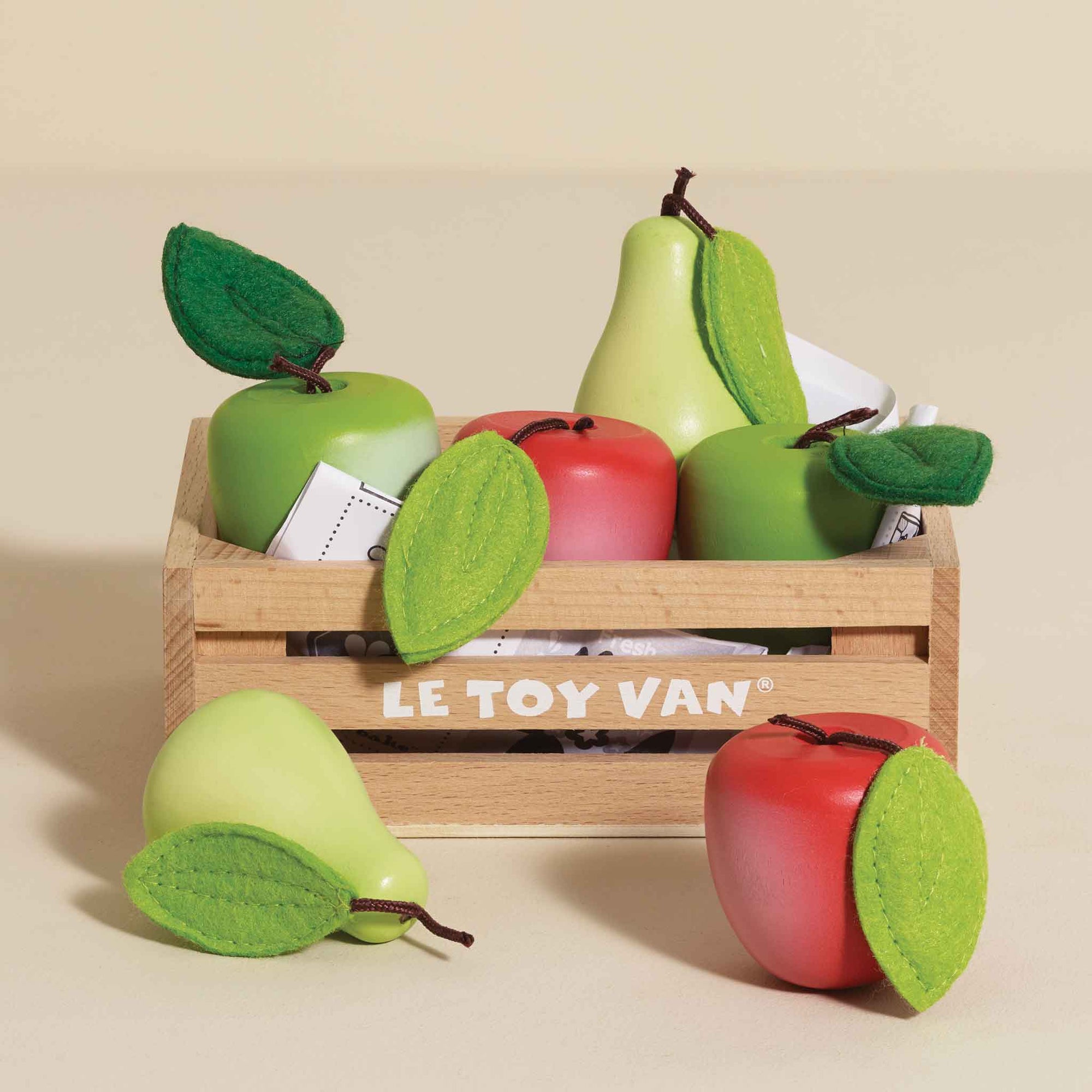 Wooden toy fruits including apples and pears in a crate with 'LE TOY VAN' branding.
