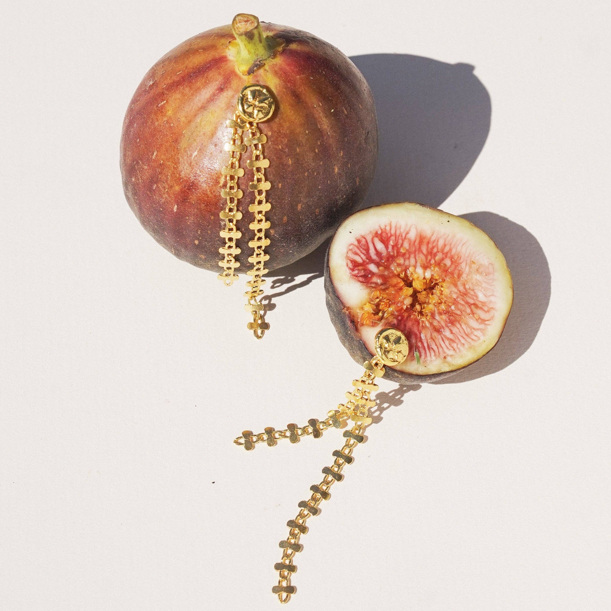 Gold earrings on figs on a light background