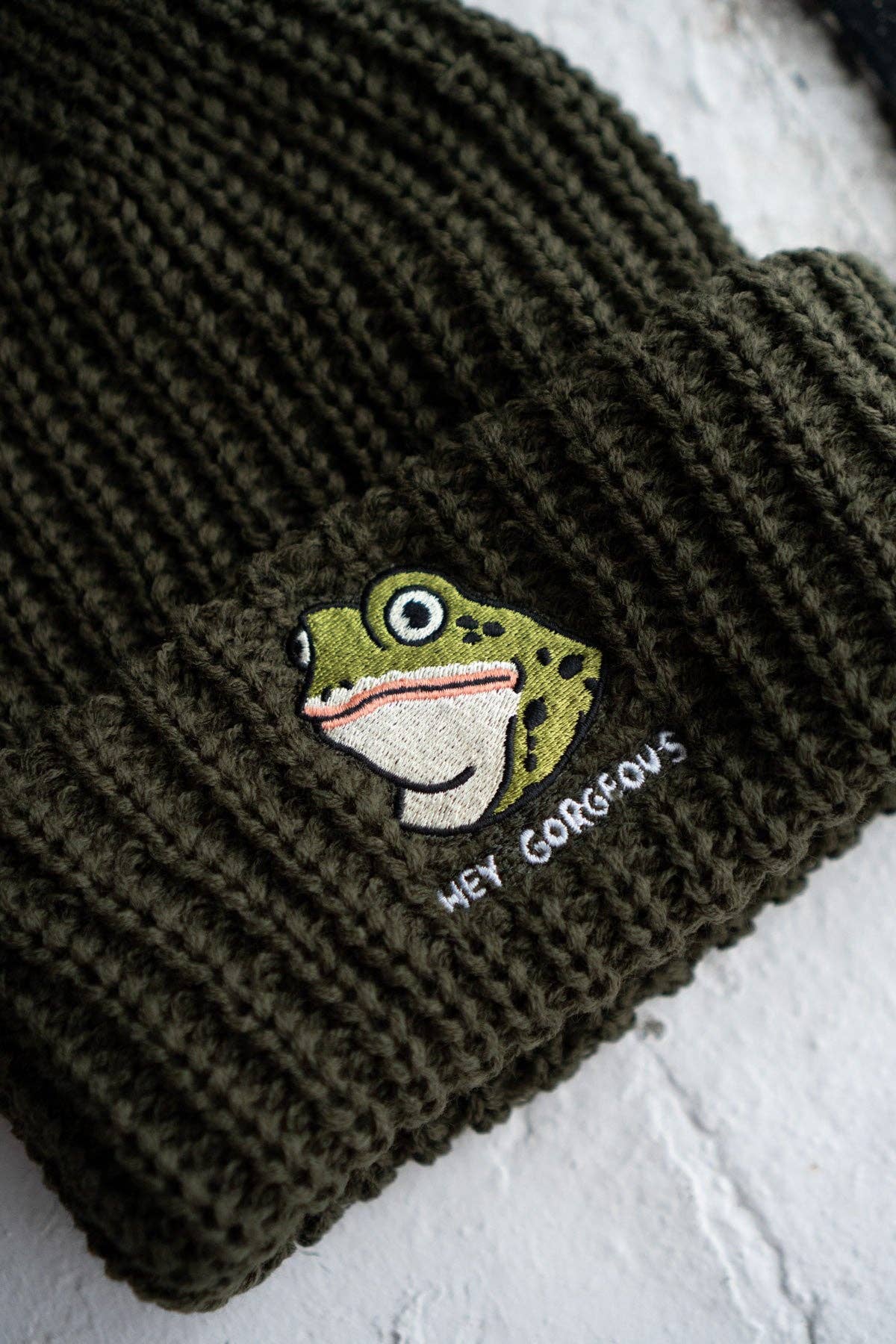 Green knit beanie with a fish embroidered design and text on a white background