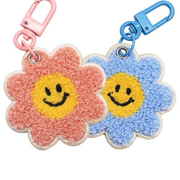 Two flower-shaped keychains with smiley faces, one pink and one blue, on a white background.