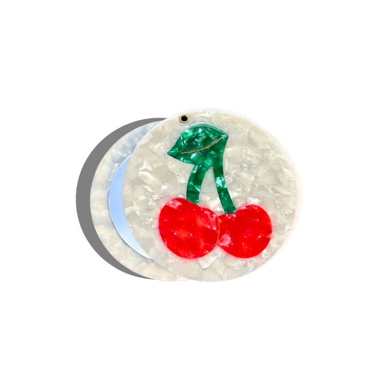 Circular object with red cherries and green leaves on a white background