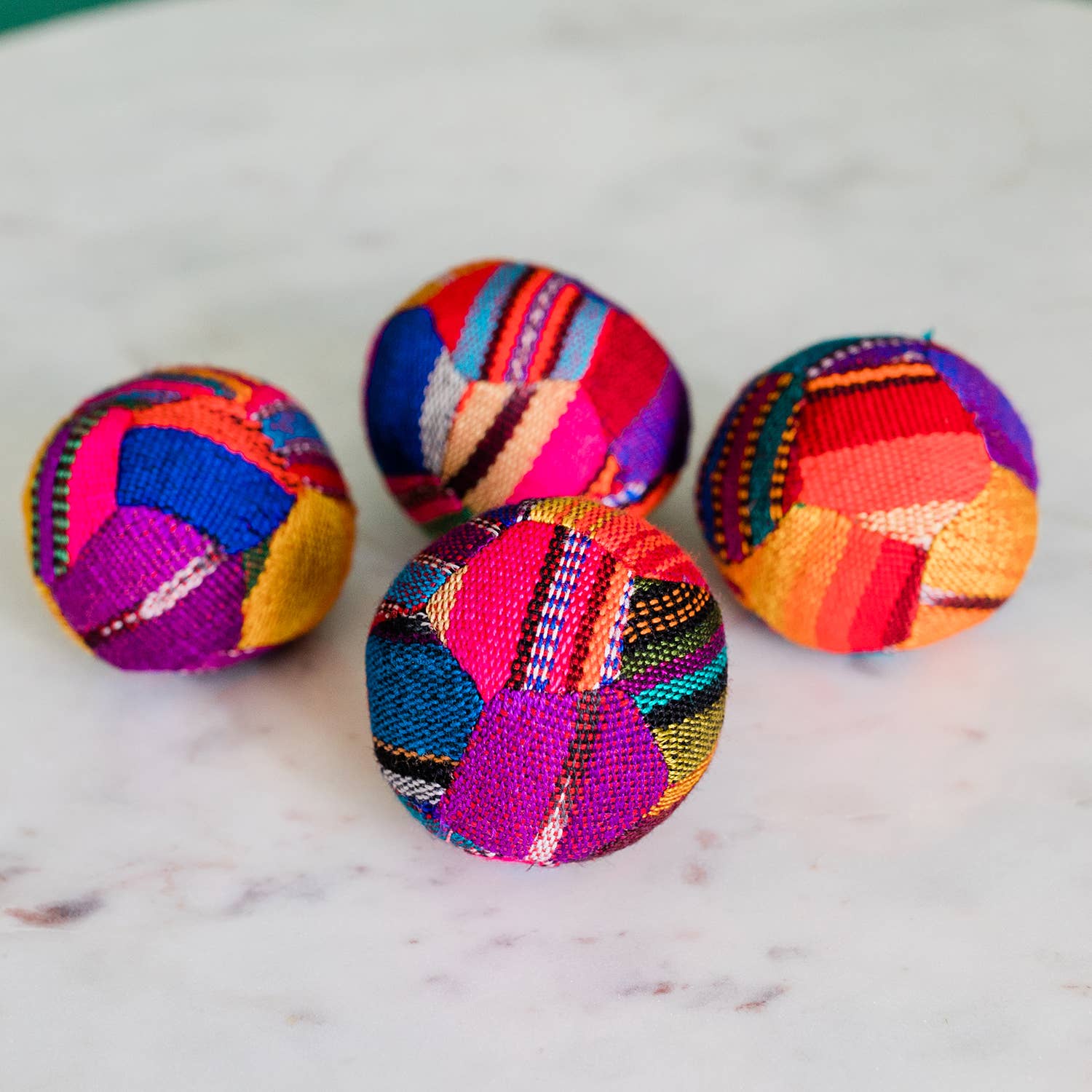 Four colorful fabric balls on a marble surface
