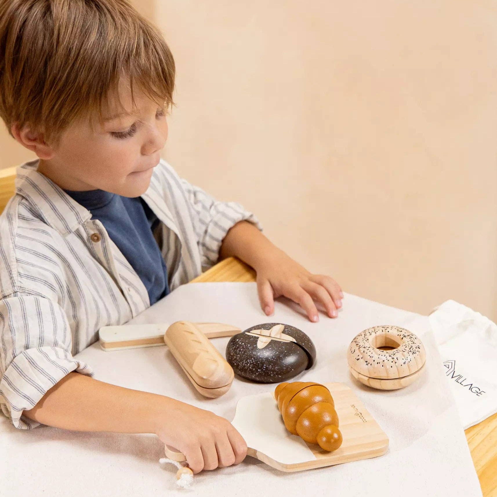 Child playing with toy donuts and utensils on a table