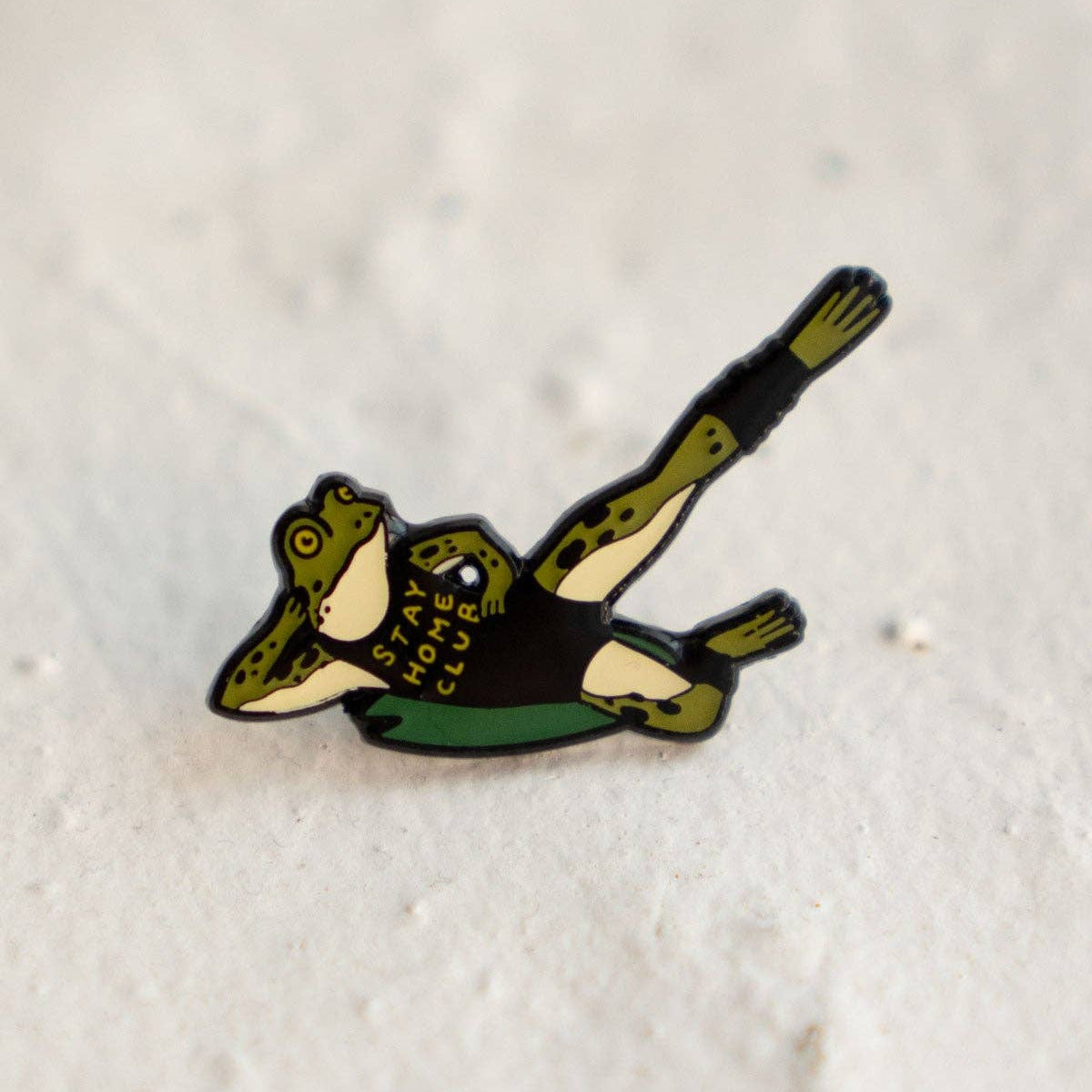 Frog-shaped badge with text on a textured white background