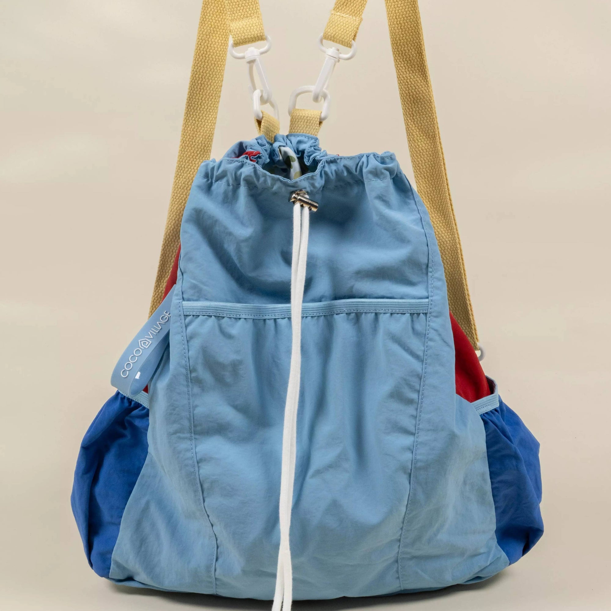 Blue drawstring bag with beige straps on a beige background