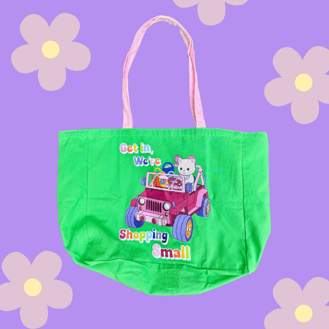 Green tote bag with a cartoon design on a purple background with flowers