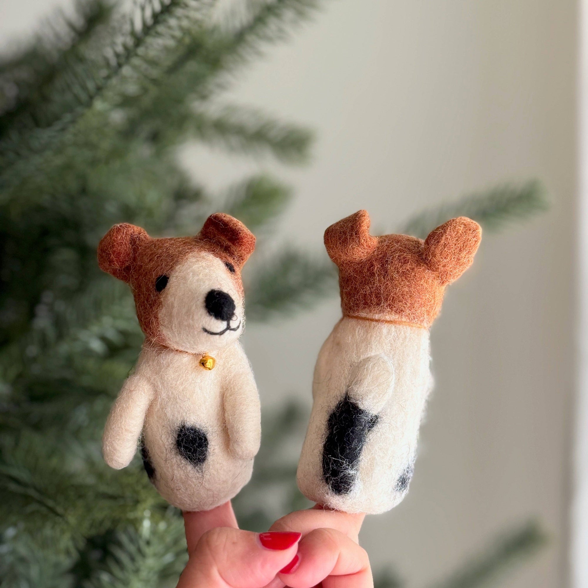 Two felt dog finger puppets held against a blurred green background