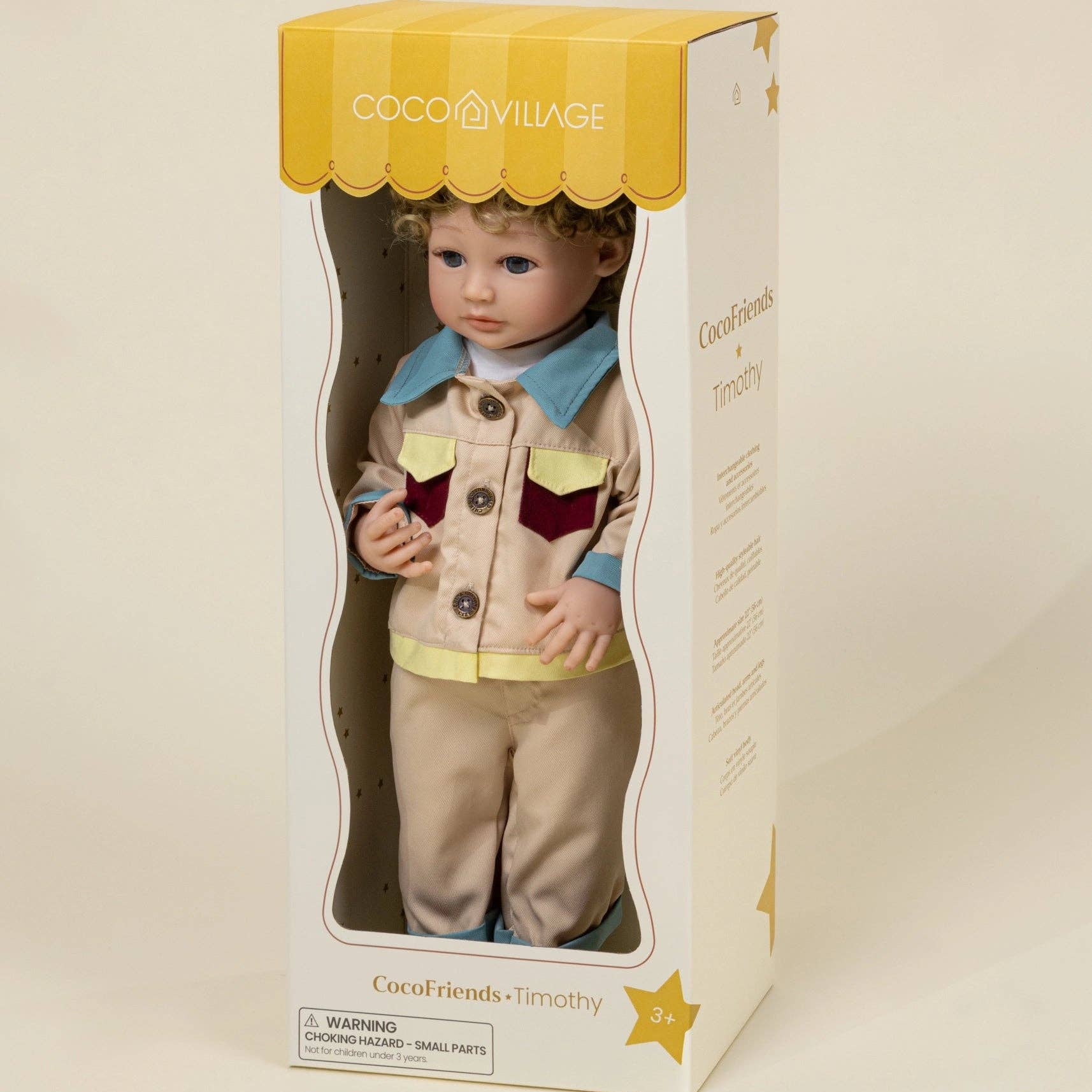 Doll in a box with a yellow and white striped lid, featuring the brand 'Cocoon Village'.