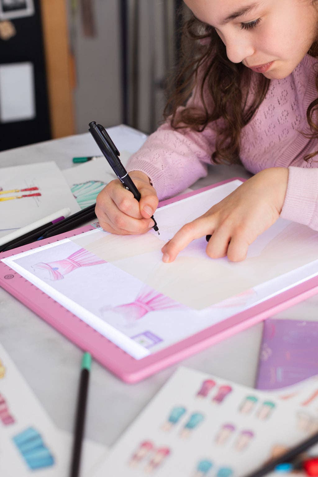 Child drawing on a lightboard with colorful markers