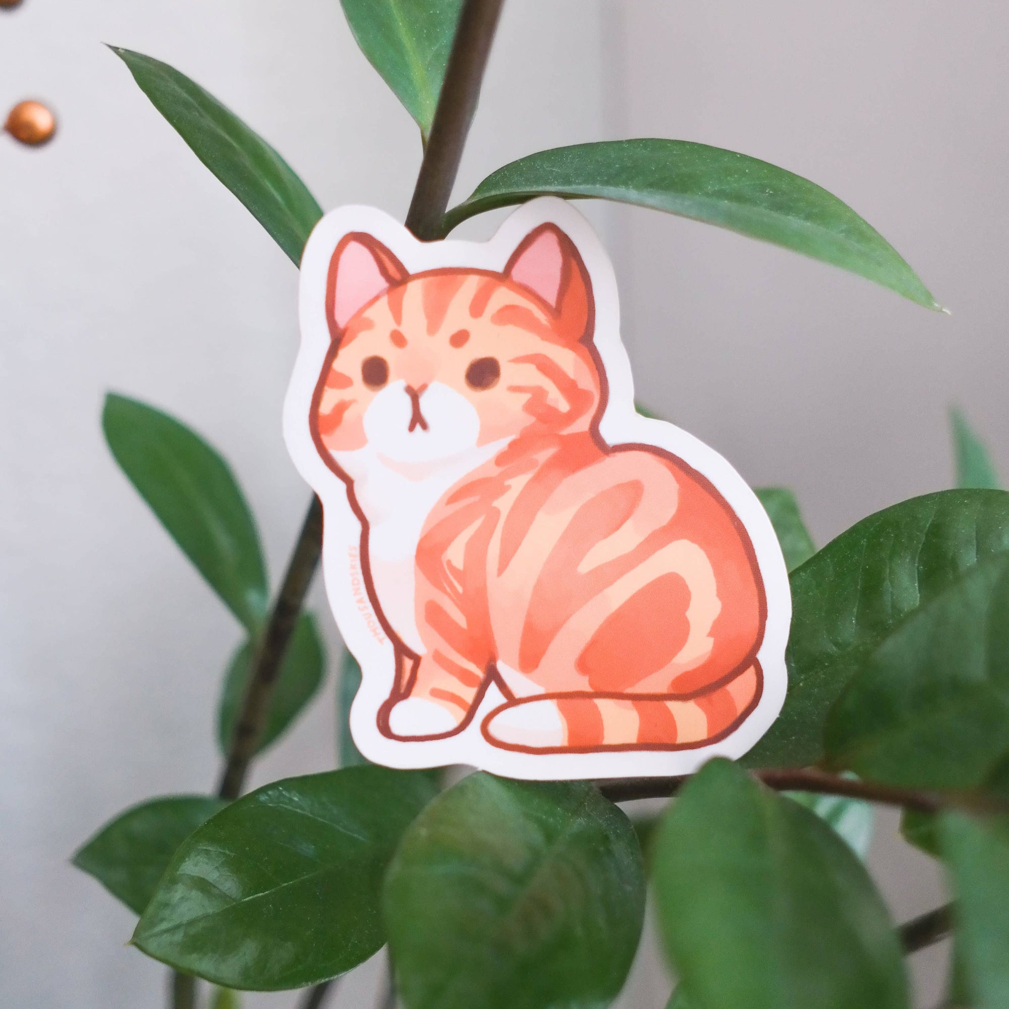 Sticker of a cartoon cat on a leafy green plant
