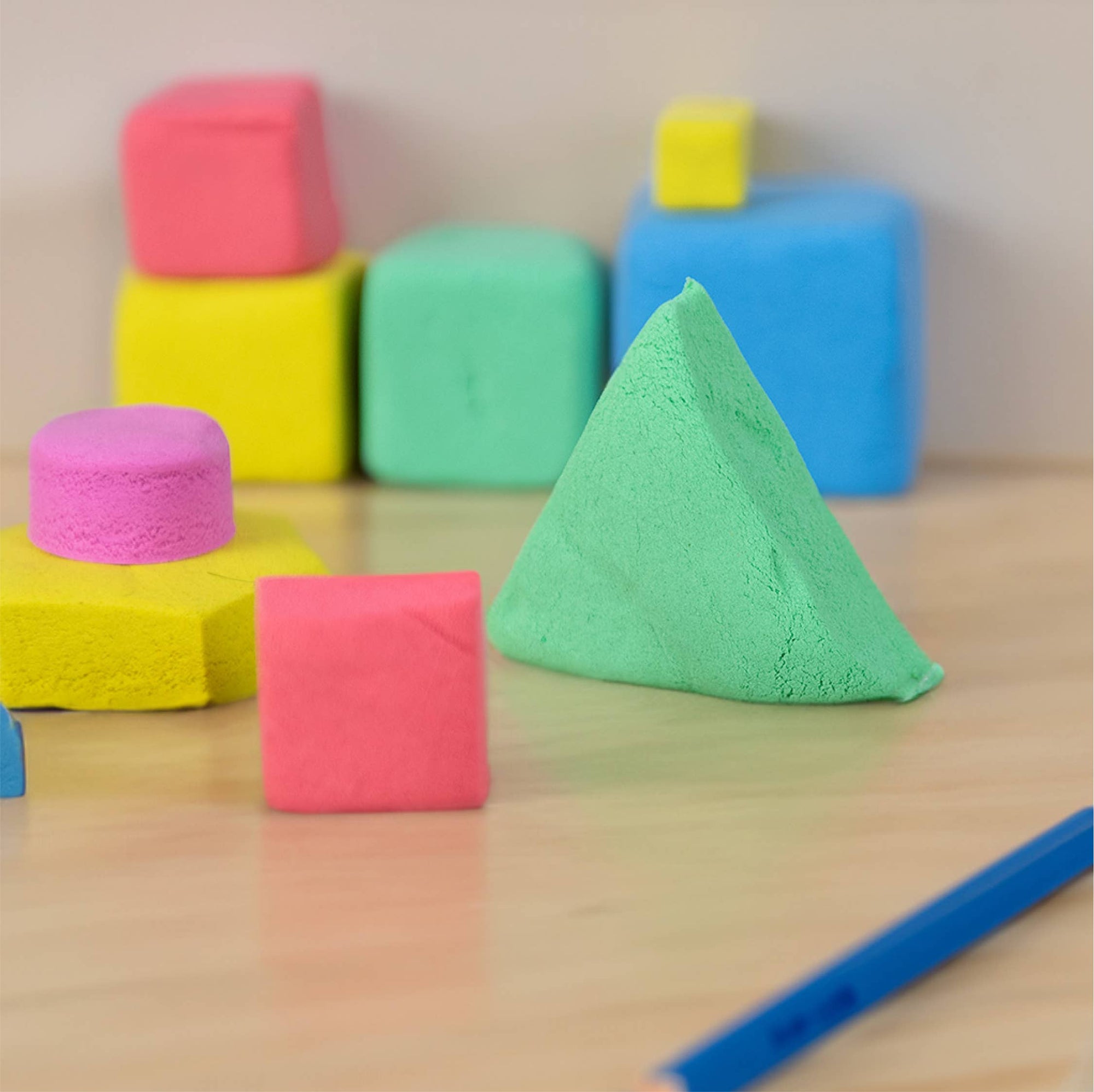 Colorful foam blocks on a wooden surface with a pen.