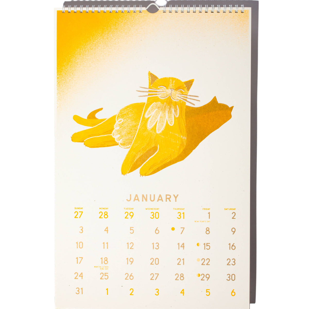 A January desk calendar with a minimalist illustration of a yellow cat on an off-white page, shown standing upright against a white background.