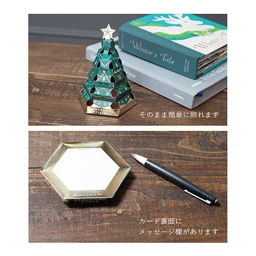Decorative Christmas tree-shaped product on a wooden surface with books and a pen.