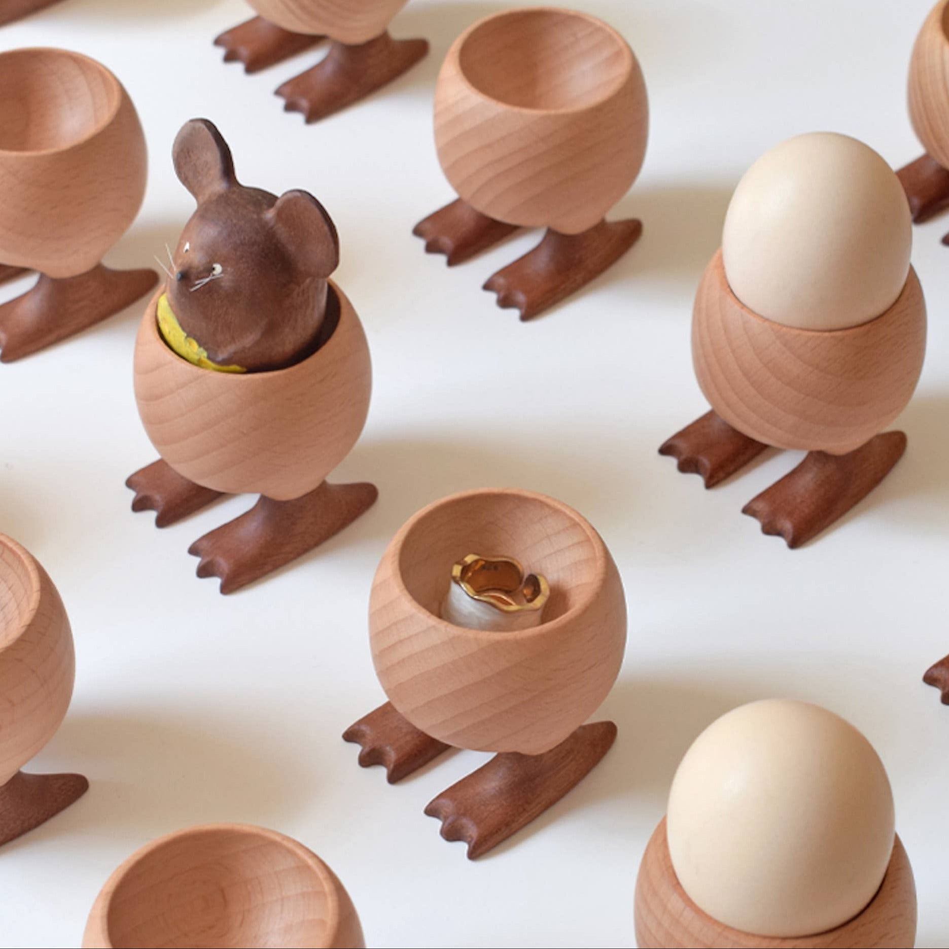 Wooden egg cups with duck feet on a white background