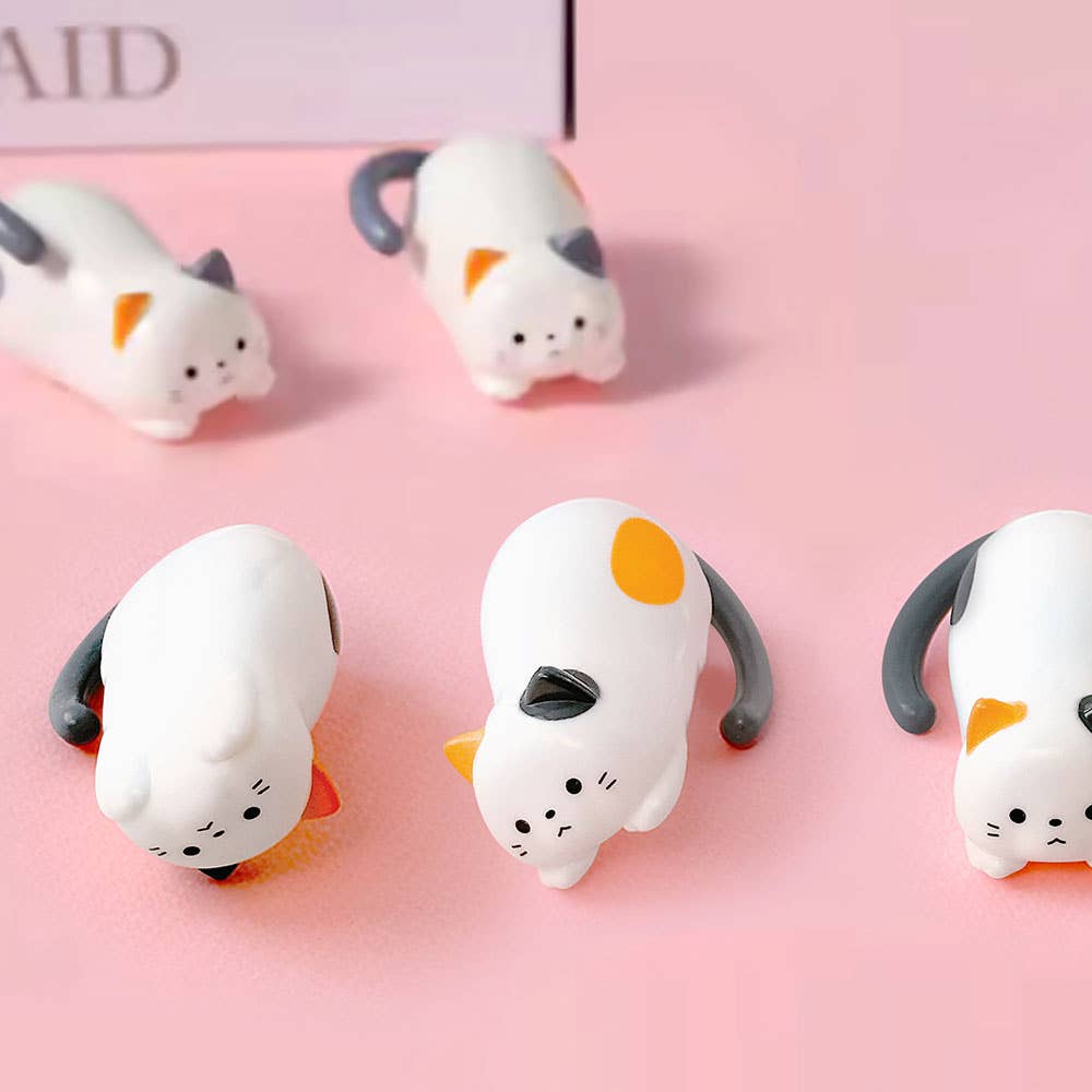 Cute cat-shaped winding toys on a pink background