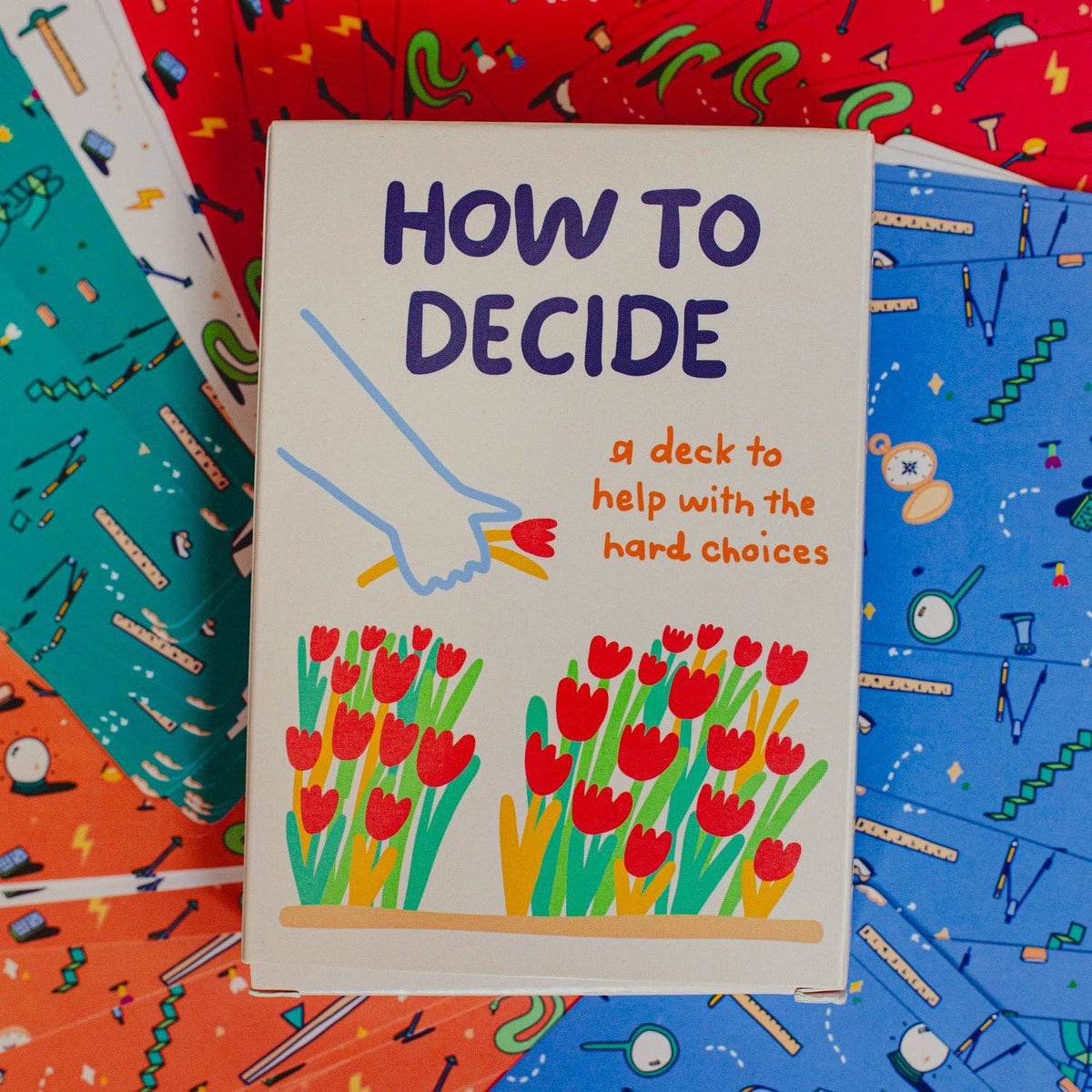 Card game box titled 'How to Decide' with colorful design on a patterned background