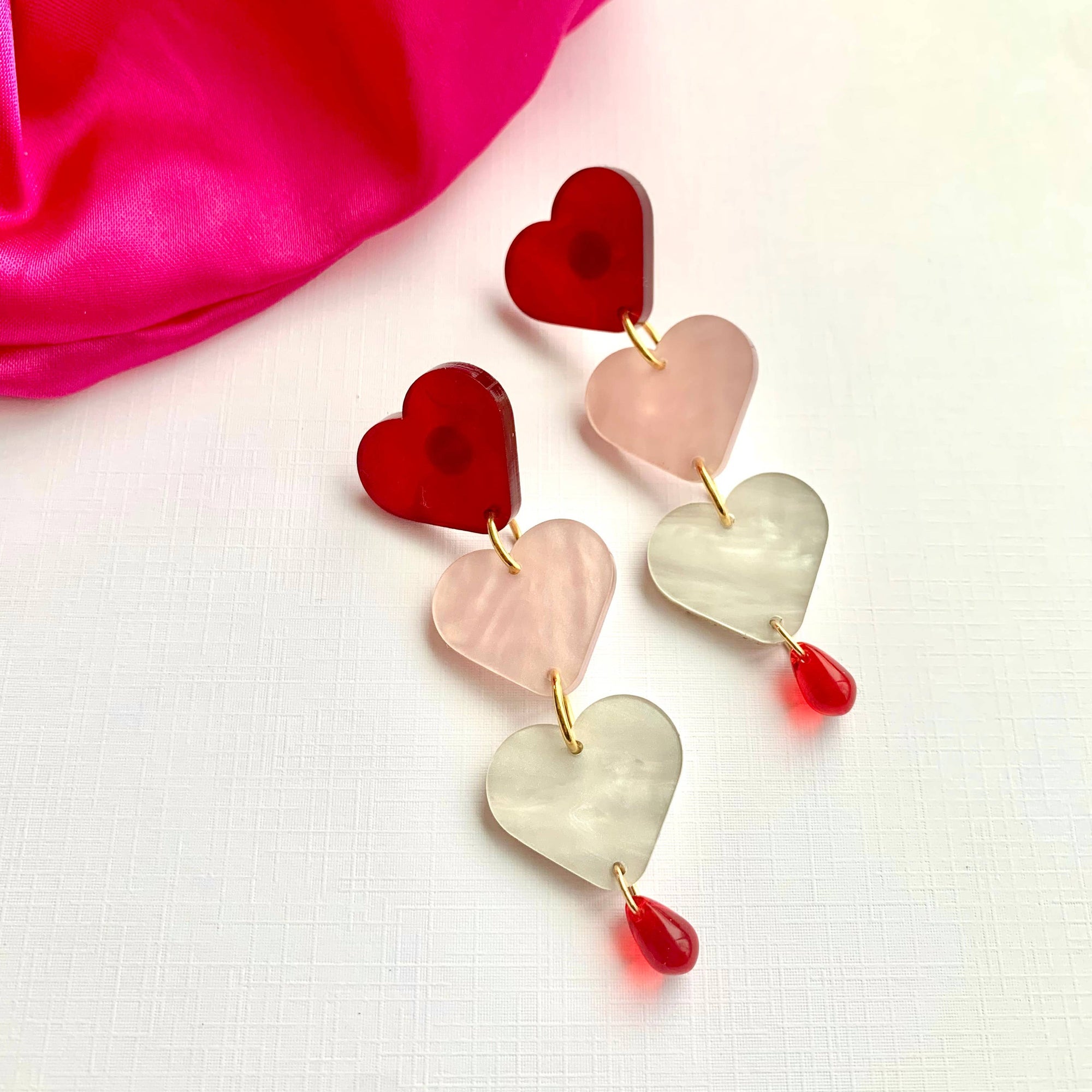 Heart-shaped earrings on a pink fabric background