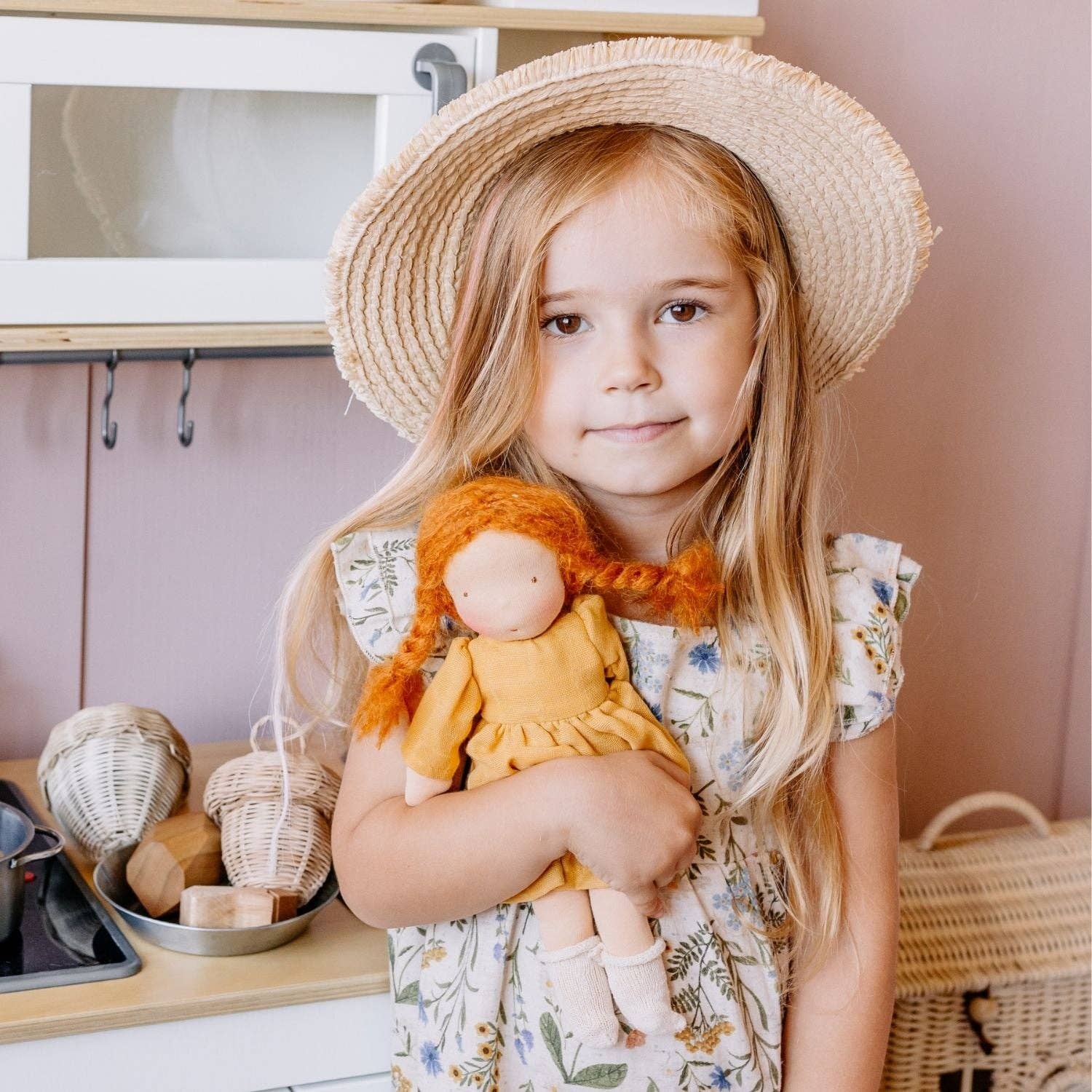 Young girl holding a doll in a kitchen setting
