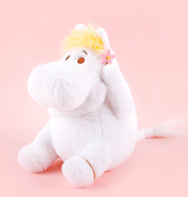 White plush toy with yellow hair and pink flower on a pink background