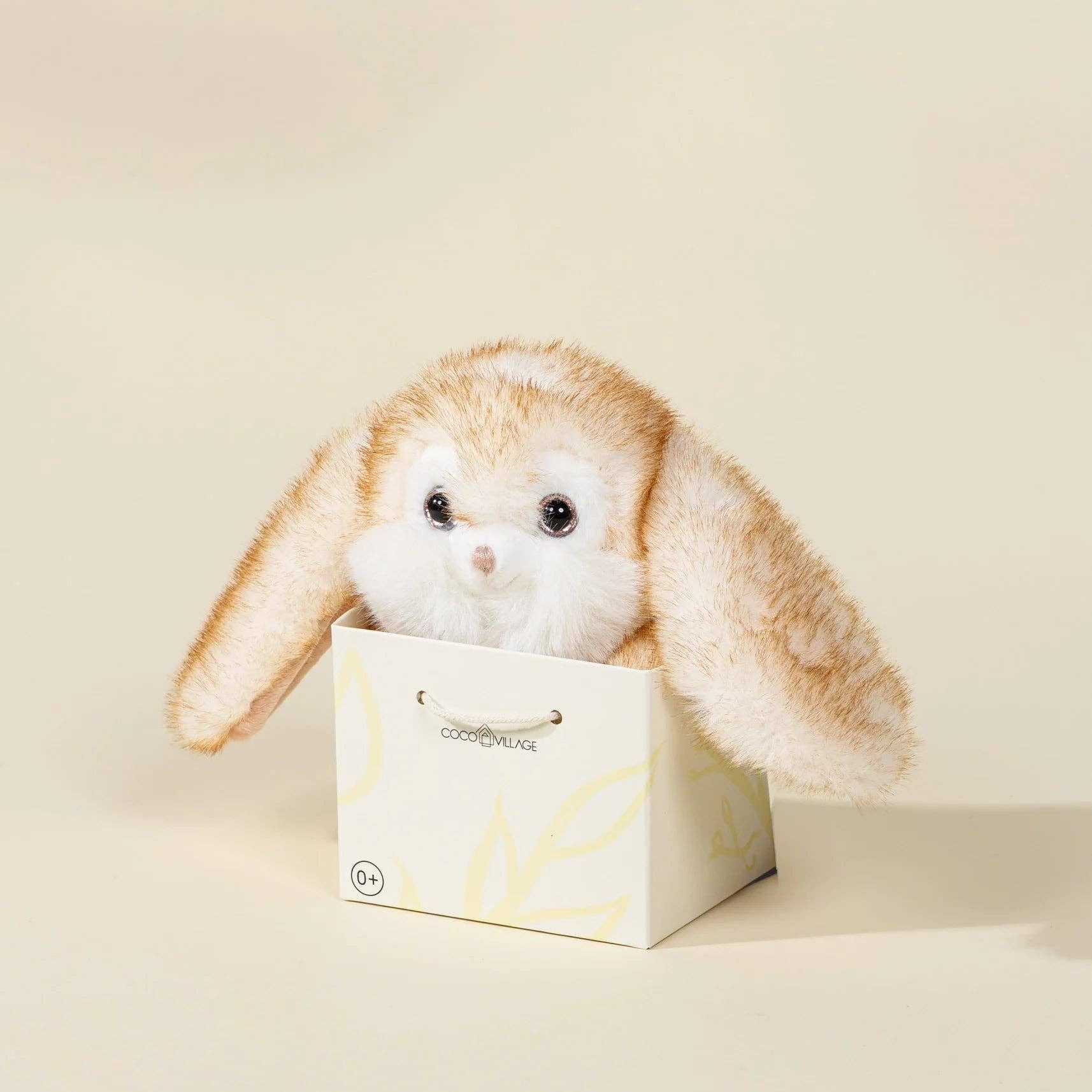 Plush bunny toy in a white box on a beige background