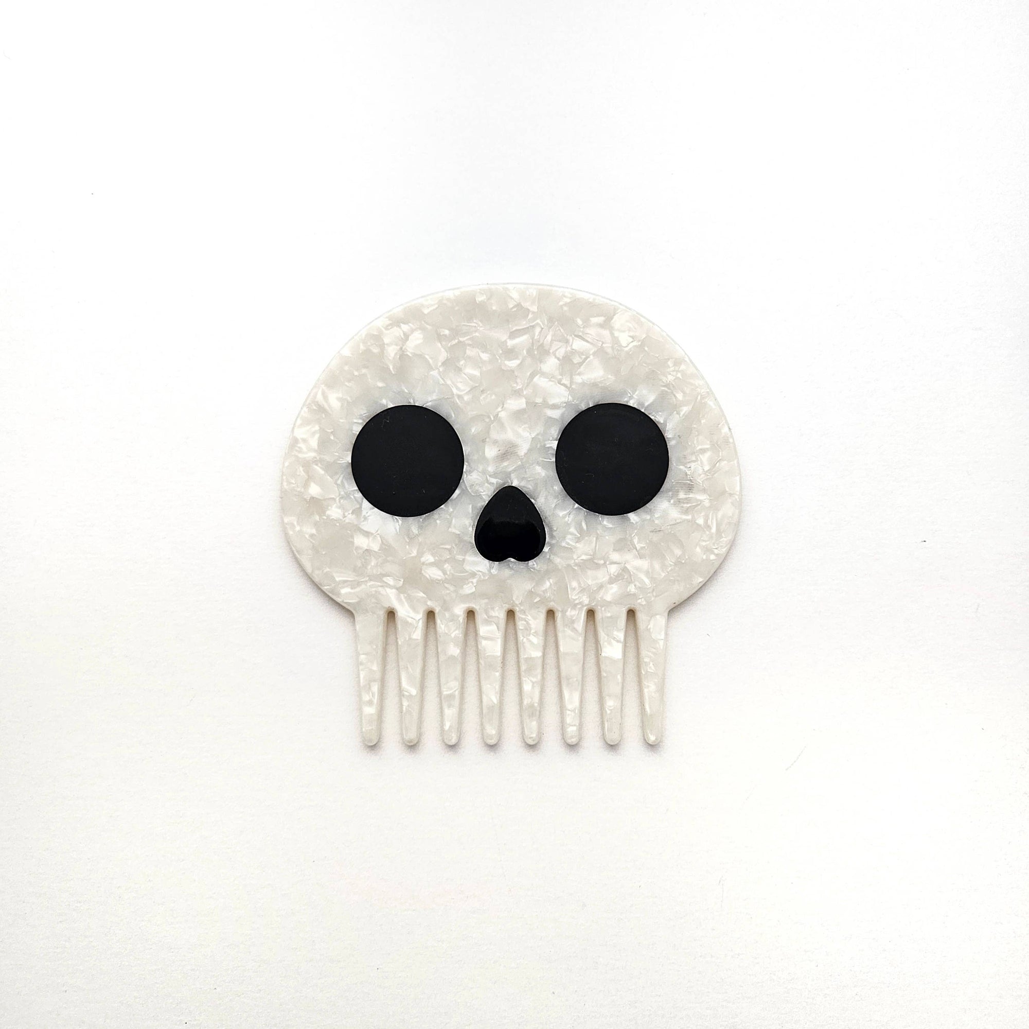 Skull-shaped hair comb with black details on a white background