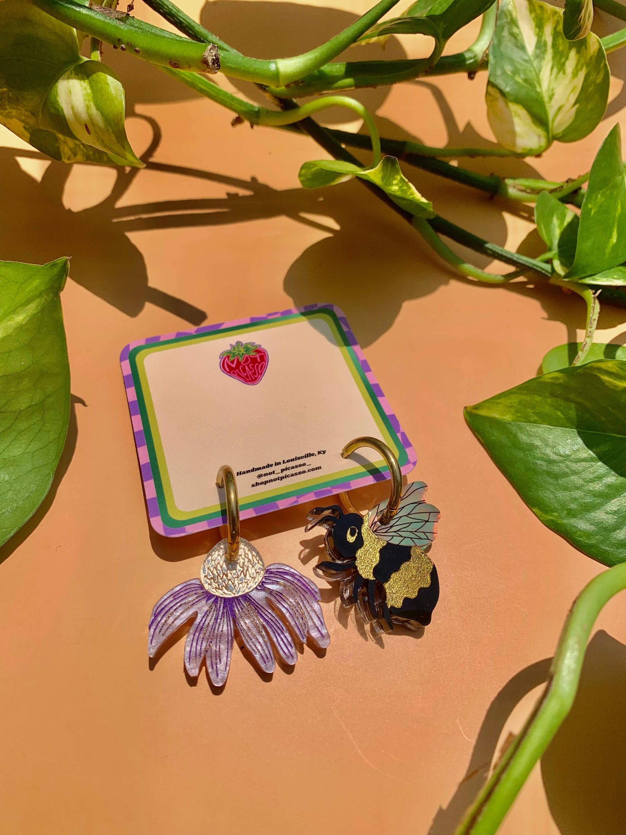 Two keychains on a card with green leaves in the background