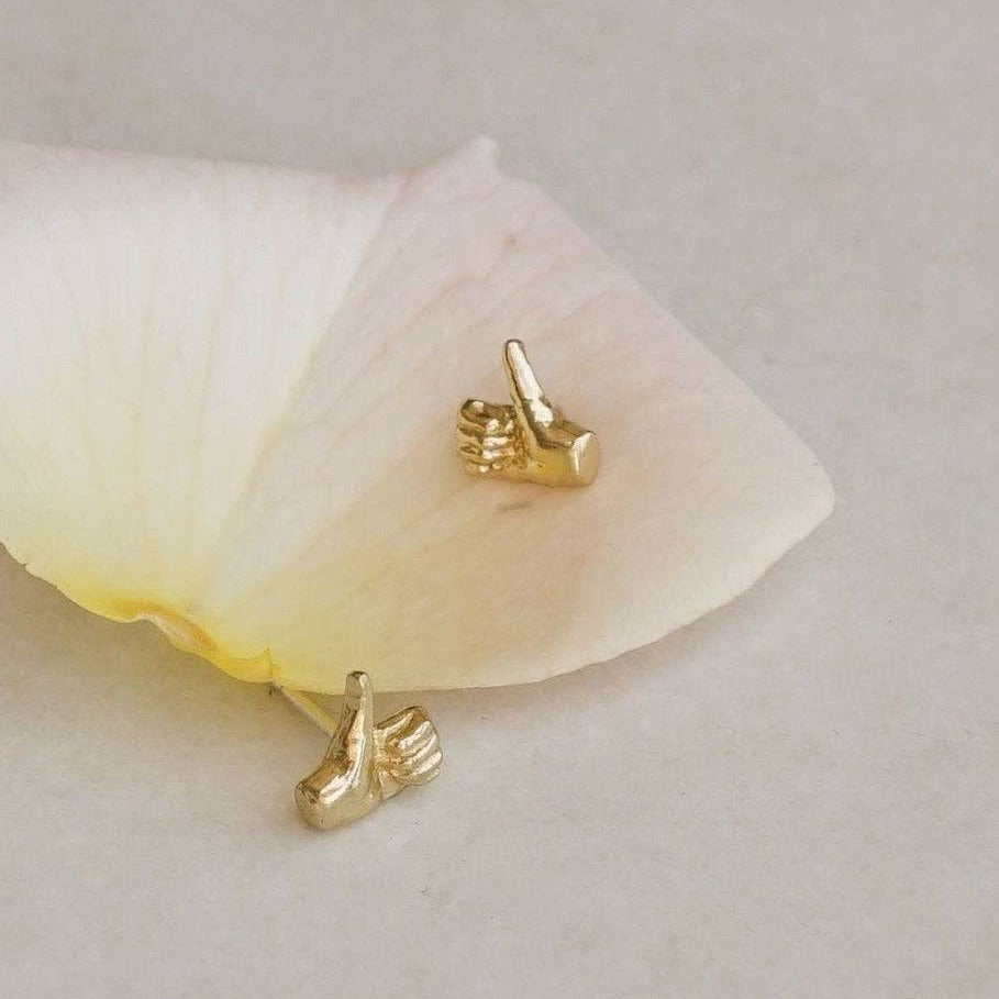 Gold shoe-shaped earrings on a white flower petal