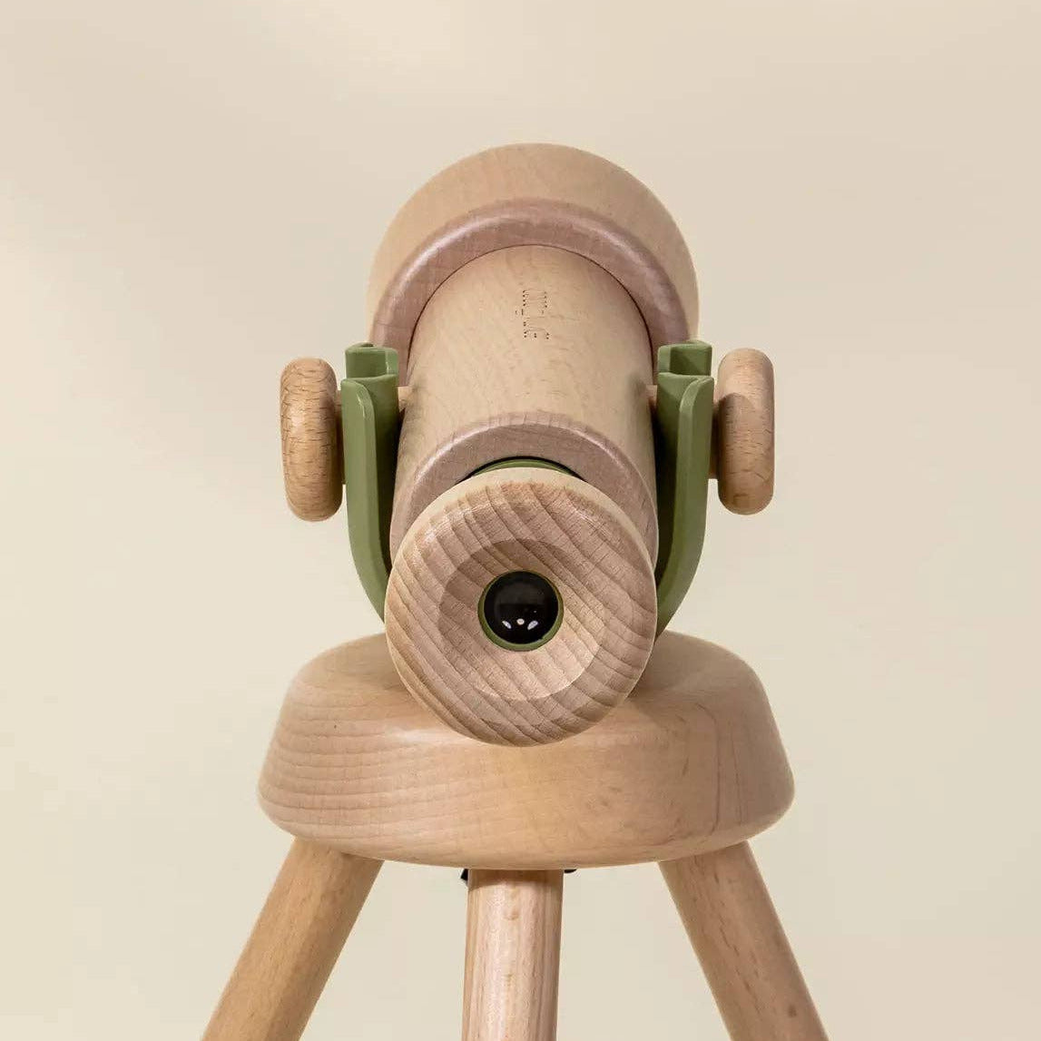Wooden toy telescope on a stand against a beige background