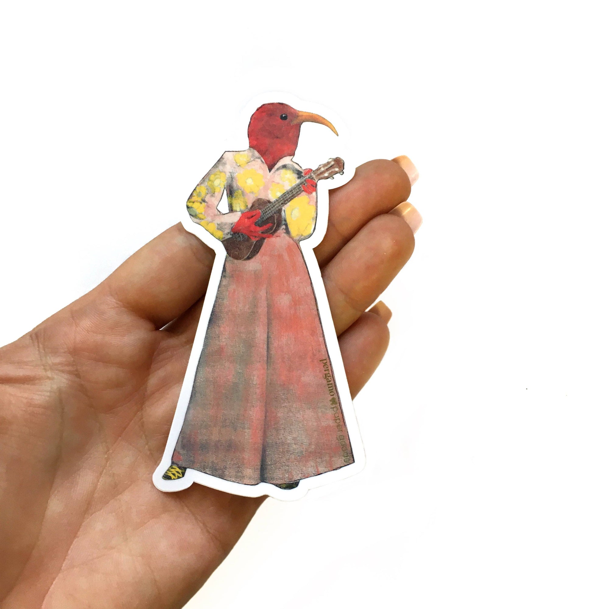 Hand holding a sticker of a colorful bird-like character playing a guitar on a white background