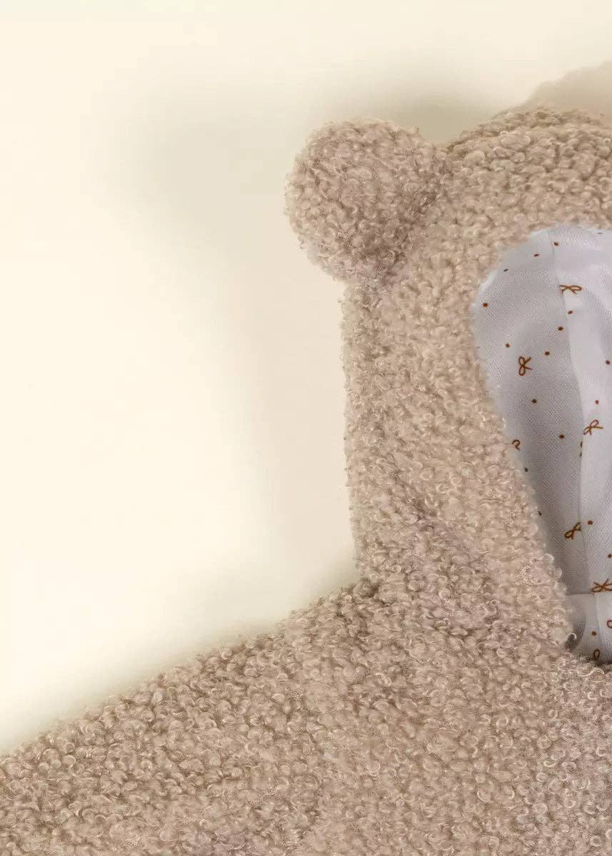 Close-up of a beige teddy bear with a white paw on a light background