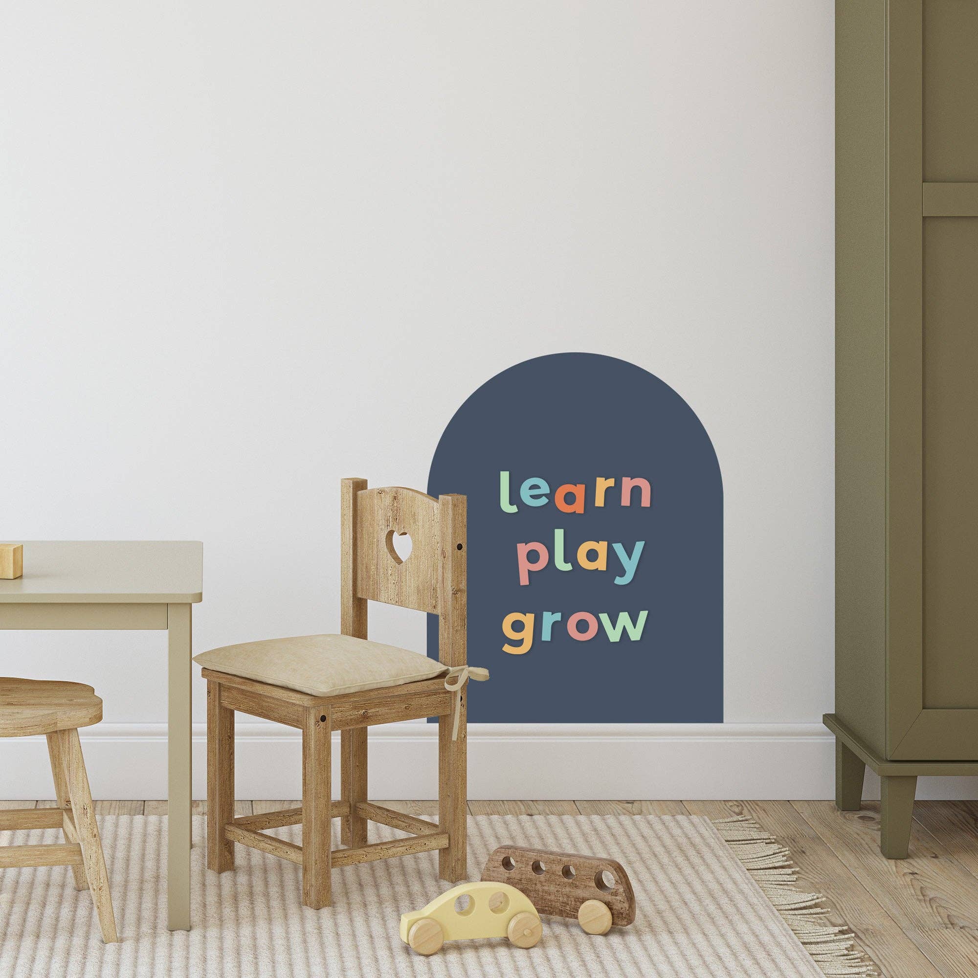 Children's room with wooden furniture and a wall decal reading 'learn play grow'.