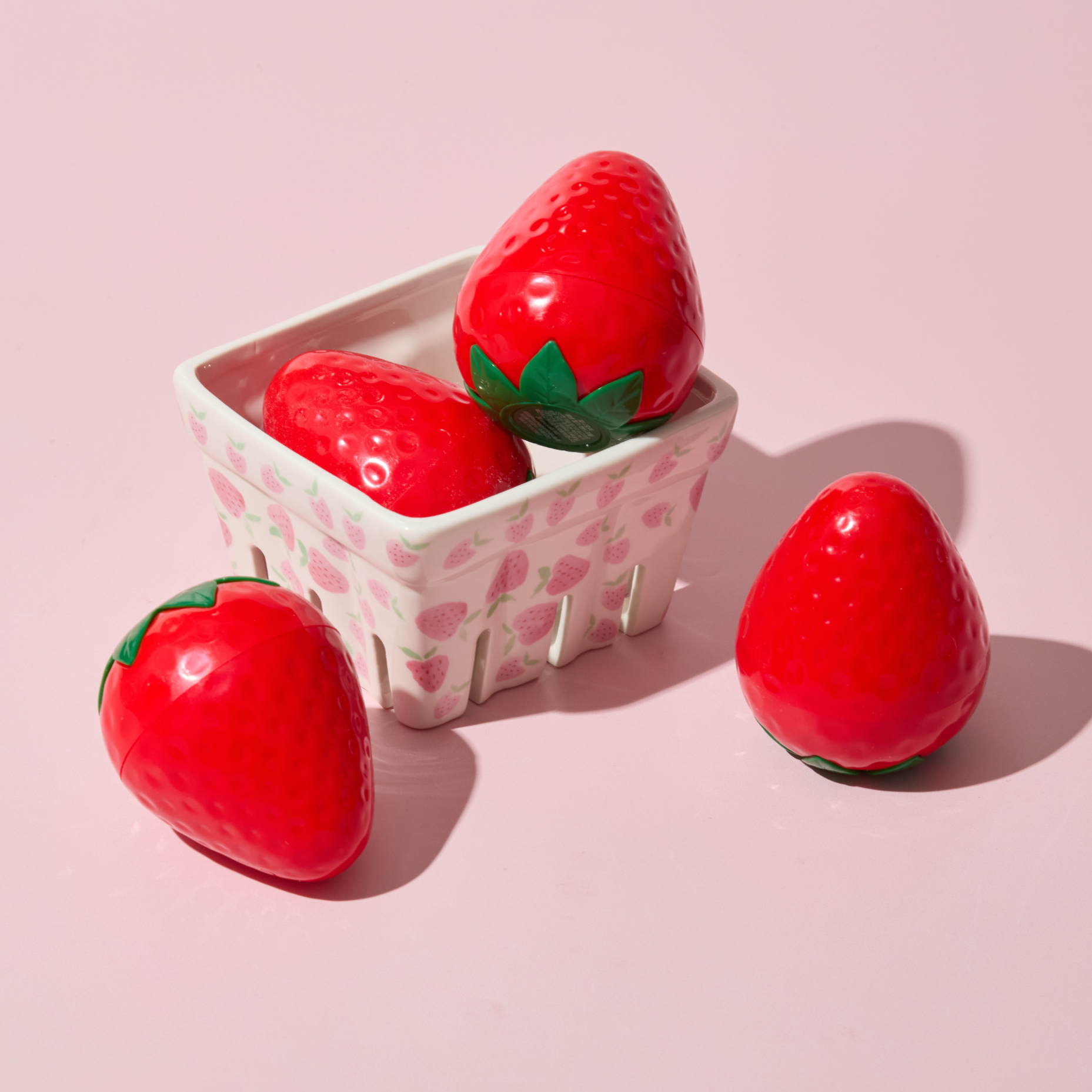 Strawberry-shaped items in a container on a pink background