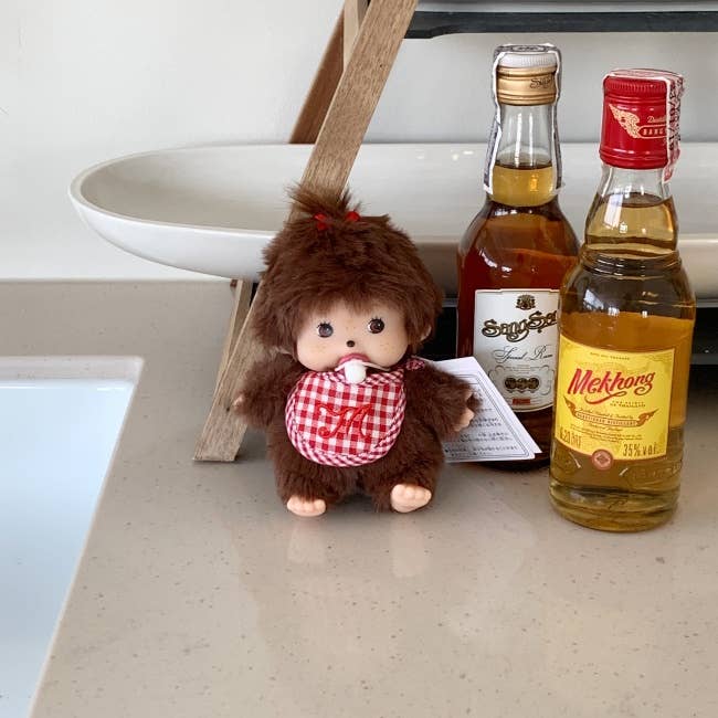 Small monkey figurine with a bottle of Meikhong wine on a surface