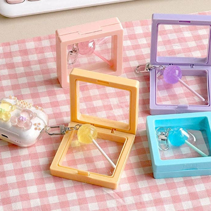 Colorful small rectangular cases with keychains on a pink checkered background