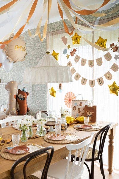 Decorated room with a table set for a celebration, featuring balloons and streamers.