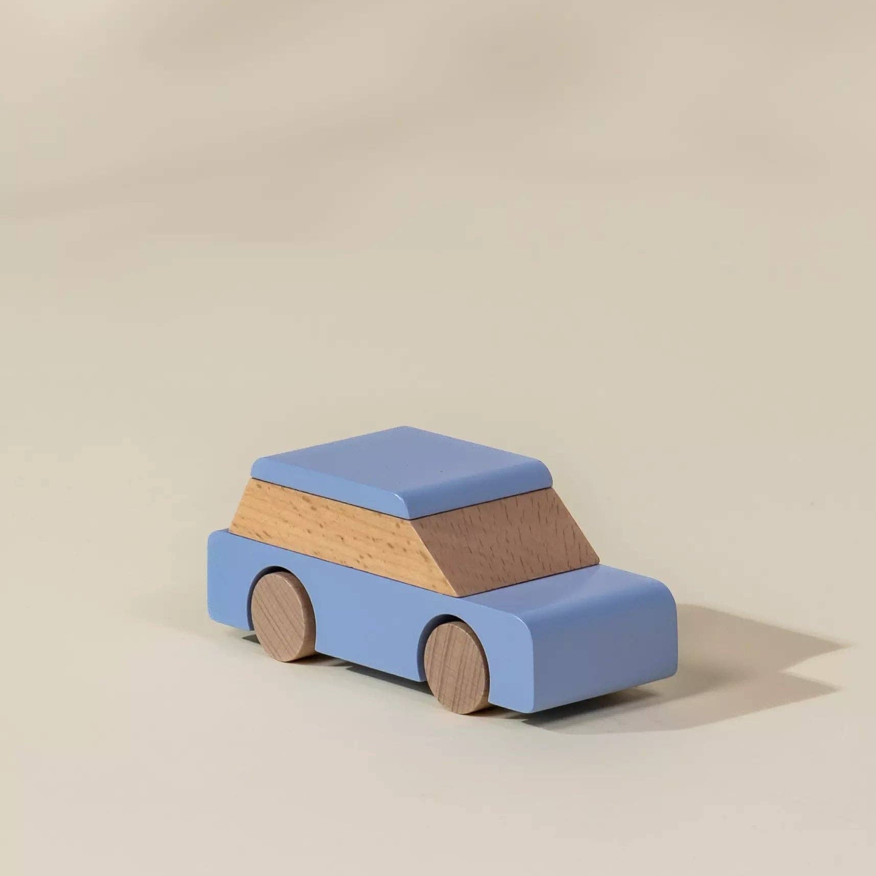 Wooden toy car with a blue body and brown roof on a beige background