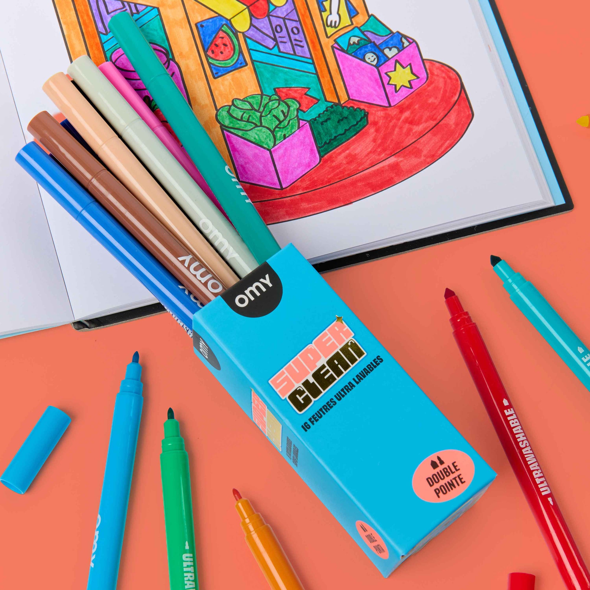 Colorful markers and a box of markers on an orange background with a coloring book.