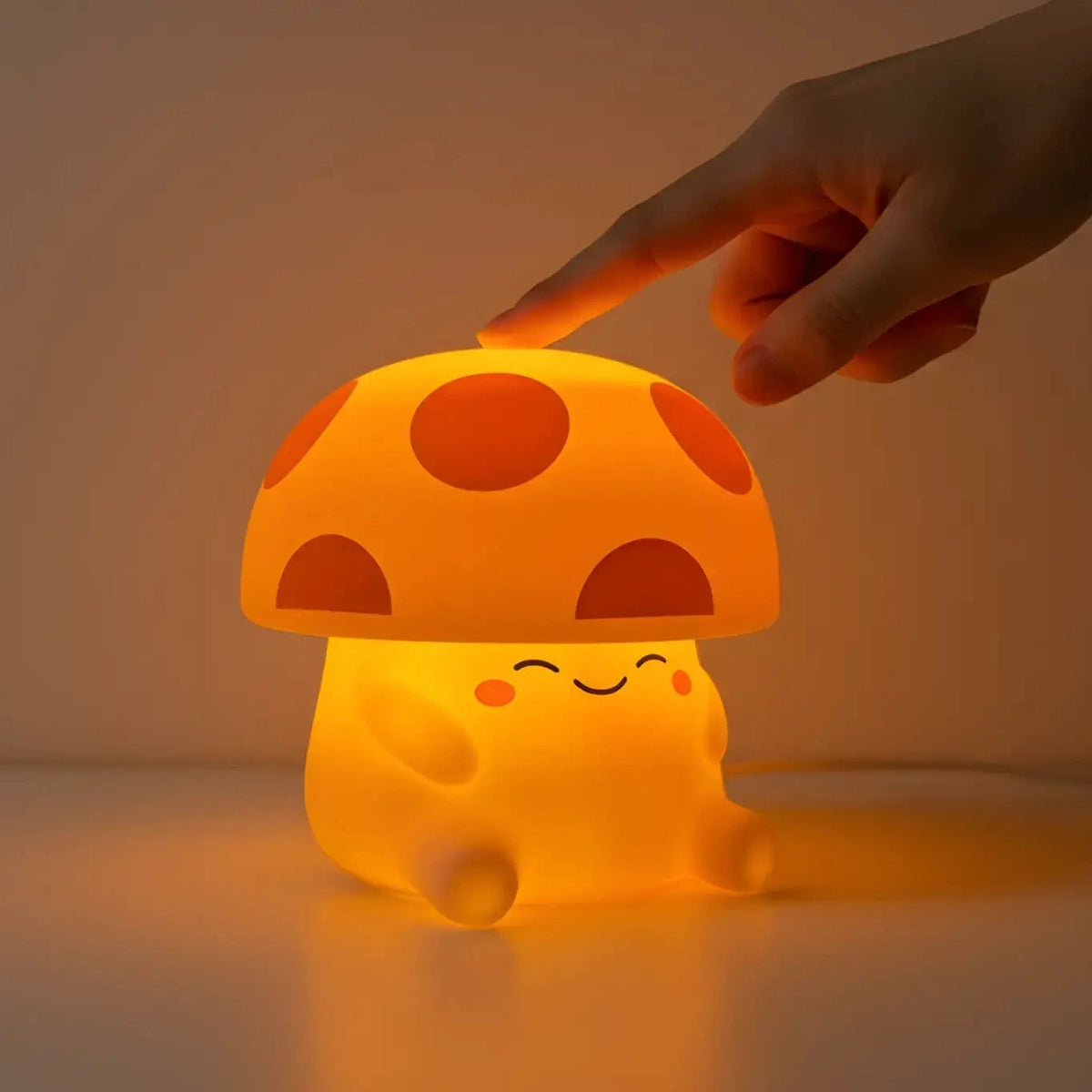 Mushroom-shaped night light with a smiling face, being touched by a hand against a neutral background.