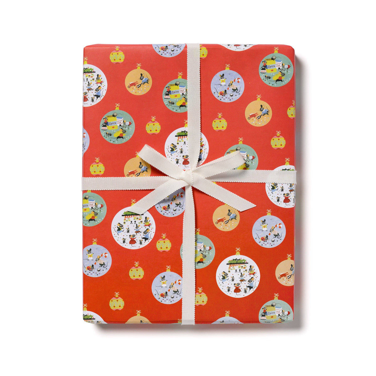 A rectangular gift box wrapped in bright red wrapping paper with a repeating pattern of cartoon pumpkins and round holiday ornaments, tied with a white ribbon and bow on a white background.