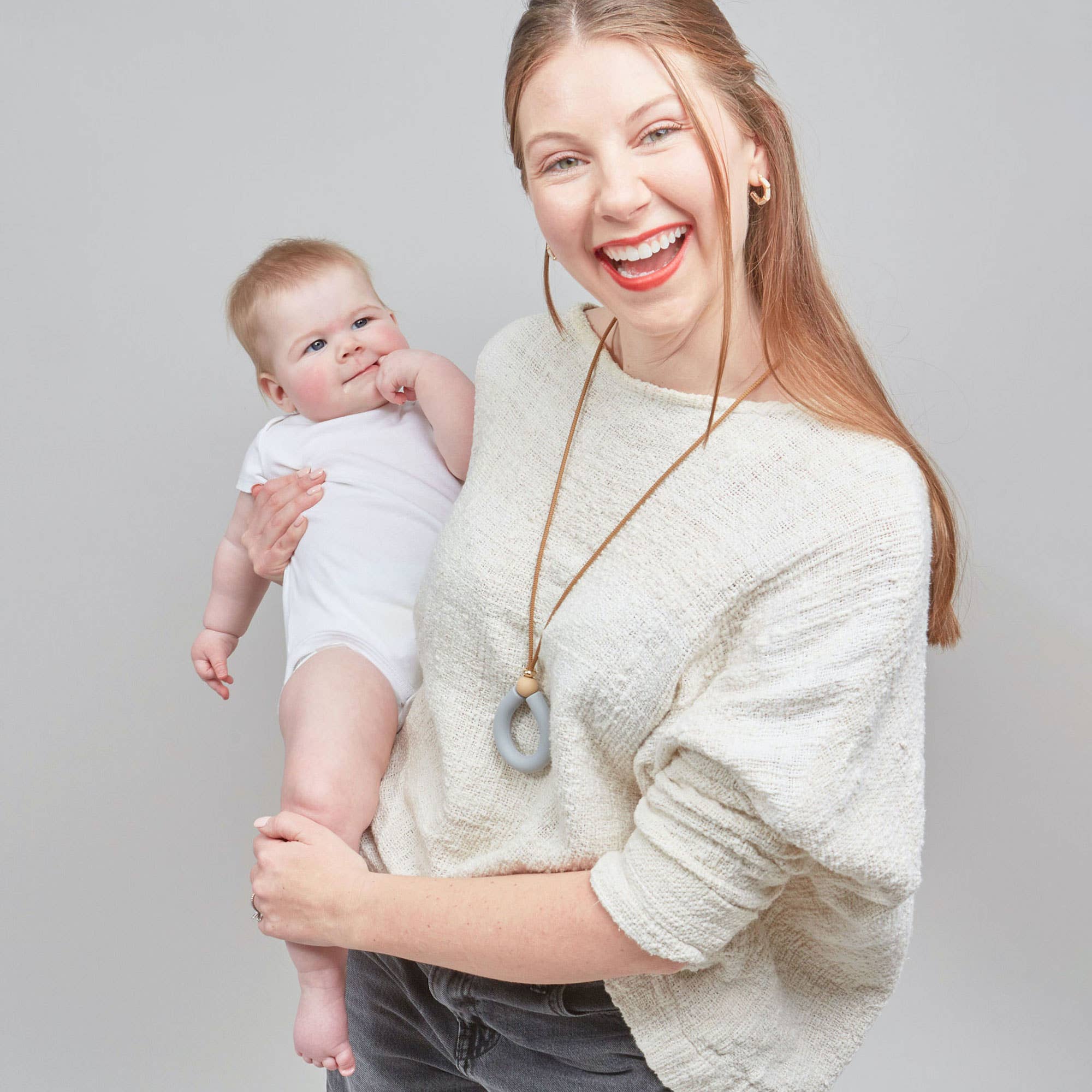 Woman holding a baby against a plain background