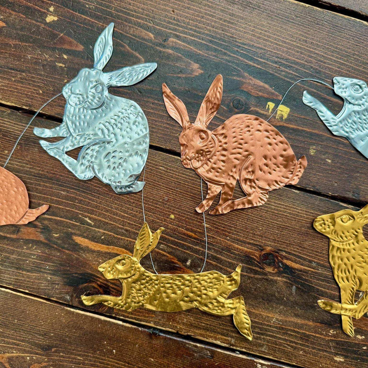 Decorative metal rabbit shapes in various colors on a wooden surface