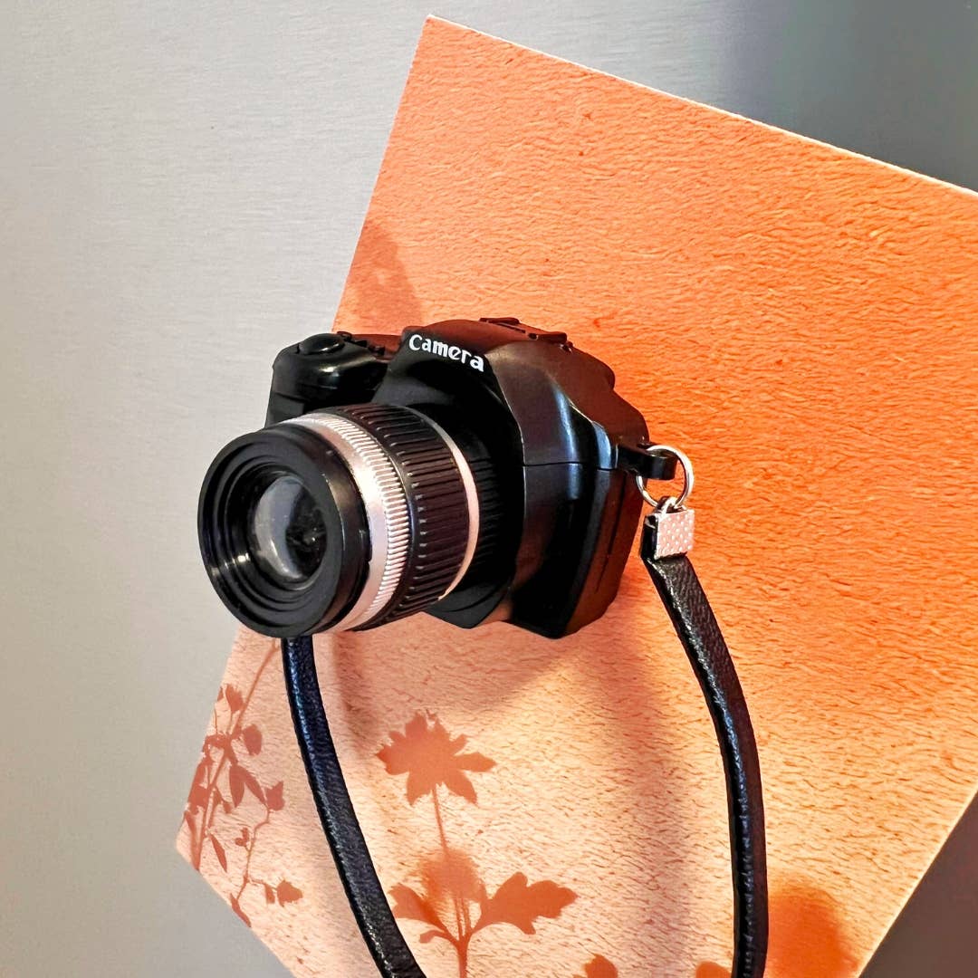 Camera with a strap on an orange surface