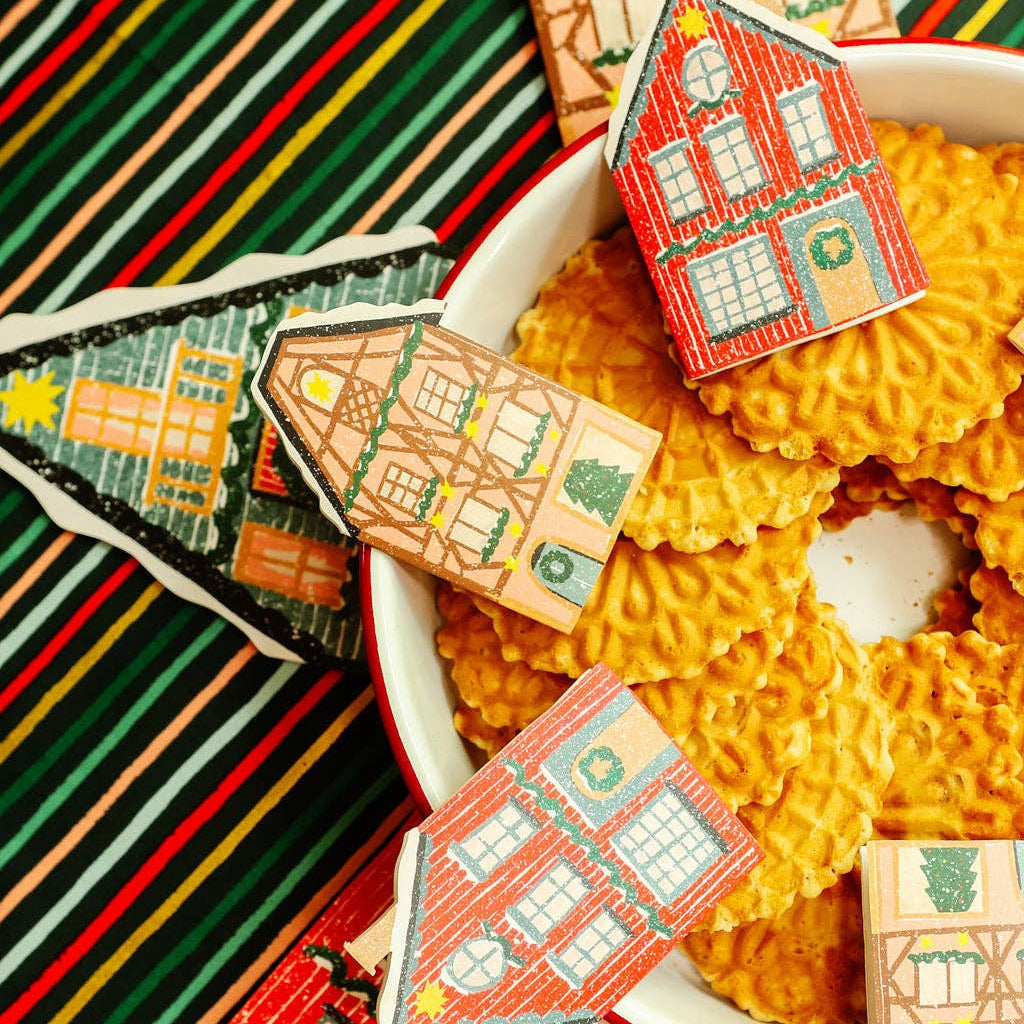 Decorative house-shaped cards on a colorful striped fabric background