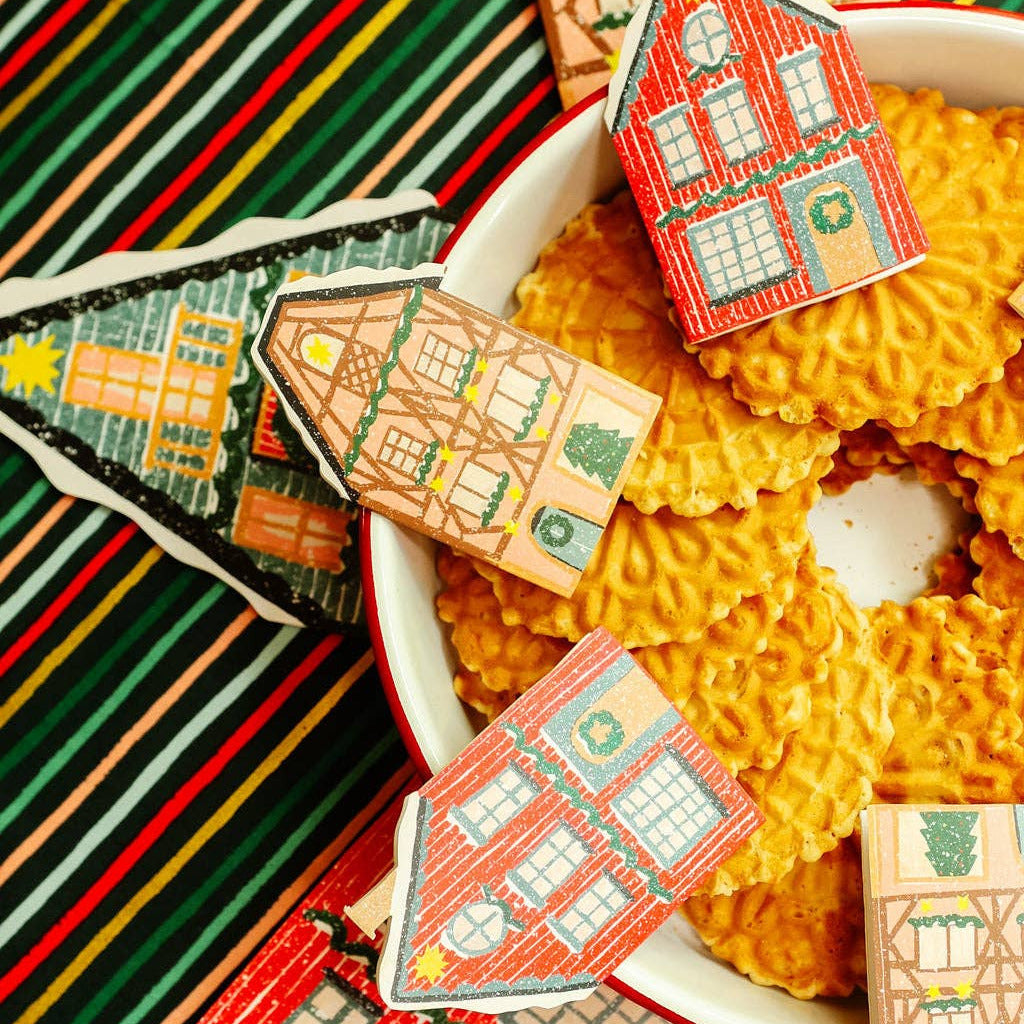 Decorative house-shaped cards on a colorful striped fabric background